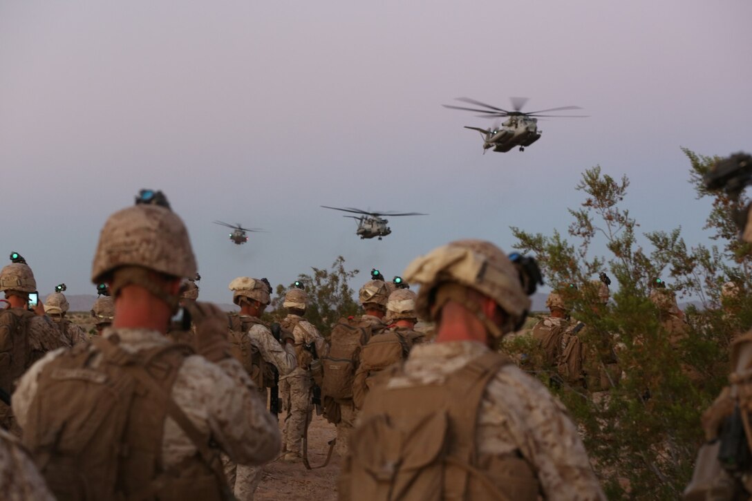 Marines with Bravo Company, 1st Battalion, 7th Marine Regiment, watch as CH-53E Super Stallion helicopters prepare to land before beginning a high value individual raid exercise here, Oct. 8, 2013. The Bravo Co. Marines inserted during night via the helicopters and patrolled to a nearby road where a Marine role playing as a suspected high-ranking insurgent traveled. Once the suspected vehicle arrived, the Marines stopped the travelers, searched and questioned each individual and searched the vehicle for weapons and other forms of intelligence. The battalion is participating in Weapons Training Instructor course before deploying to Afghanistan this spring.