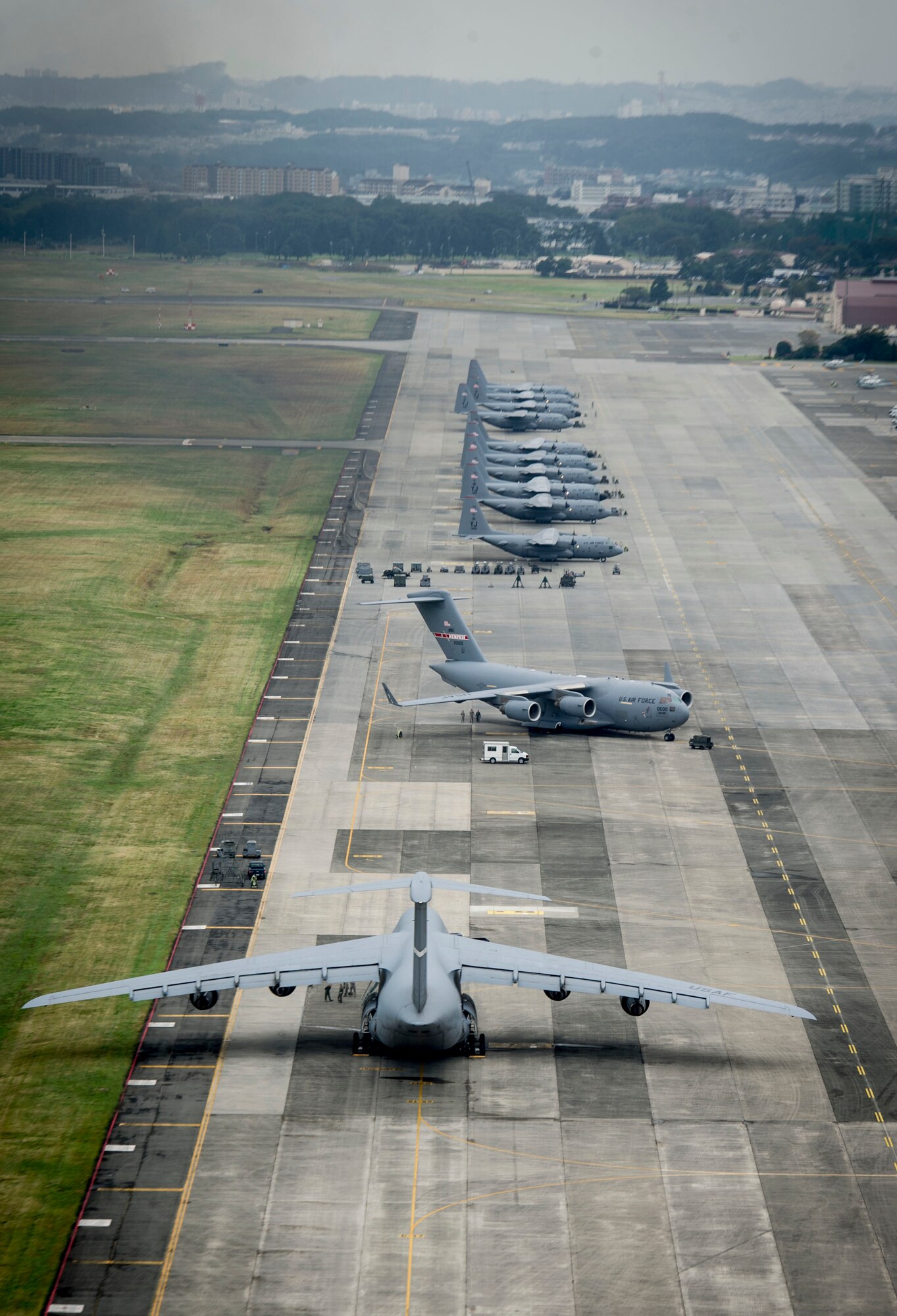 Aircraft sit on the Yokota flightline as 10 C-130 Hercules’ wait to taxi to the runway in preparation to take off as part of a large formation mission Oct. 22, 2013, at Yokota Air Base, Japan. The wing conducts surge operations to test its capability to prepare and launch multiple aircraft at the same time, highlighting Yokota’s mission as the primary Western Pacific airlift hub for peacetime and contingency operations. (U.S. Air Force photo by Staff Sgt Stacy Moless/released) 