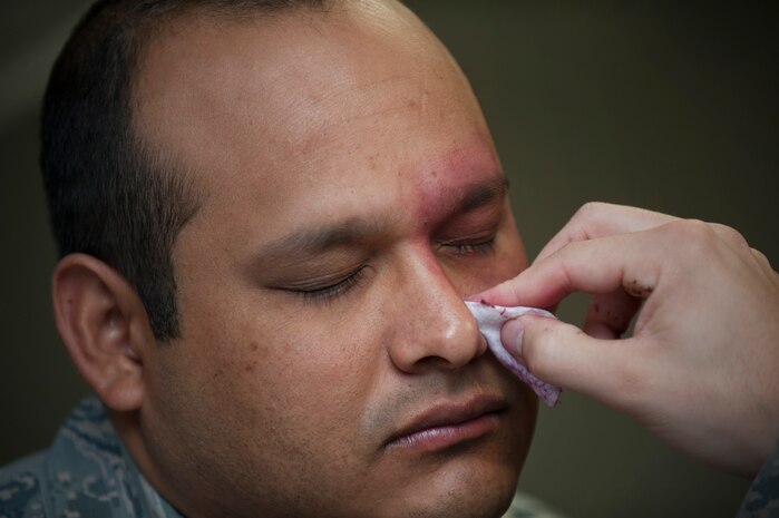 Staff Sgt. Daniel Quintana, 413th Flight Test Squadron aircrew life support craftsman, closes his eyes as makeup is applied to his face during moulage in preparation for the "Thanks for Asking” Campaign, a Domestic Abuse Awareness Month event Oct. 21, 2013, at Nellis Air Force Base, Nev. The intent of this event is to see how the base populace will react and respond when exercise participants conduct their daily operations with applied simulated bruises. (U.S. Air Force photo by Staff Sgt. Christopher Hubenthal)