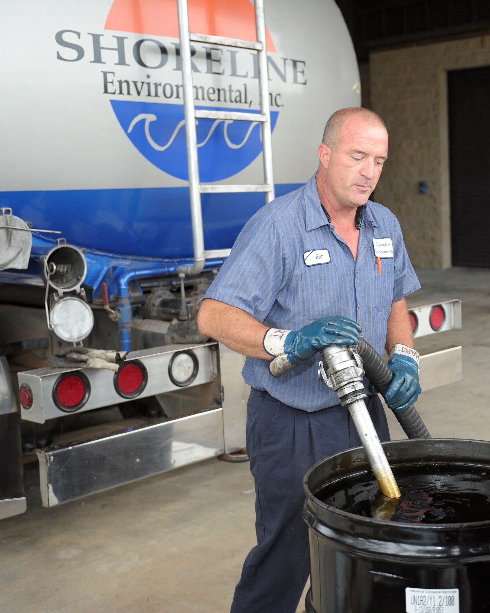 Bart Shumaker, Shoreline Environmental president, preps a hose to drain a container filled with used oil and other fluids during the Household Hazardous Waste Collection Day on Hurlburt Field, Fla., Oct. 18, 2013. The fluids were transported to a plant to be recycled into a reusable fuel. (U.S. Air Force photo/Senior Airman Kentavist P. Brackin)