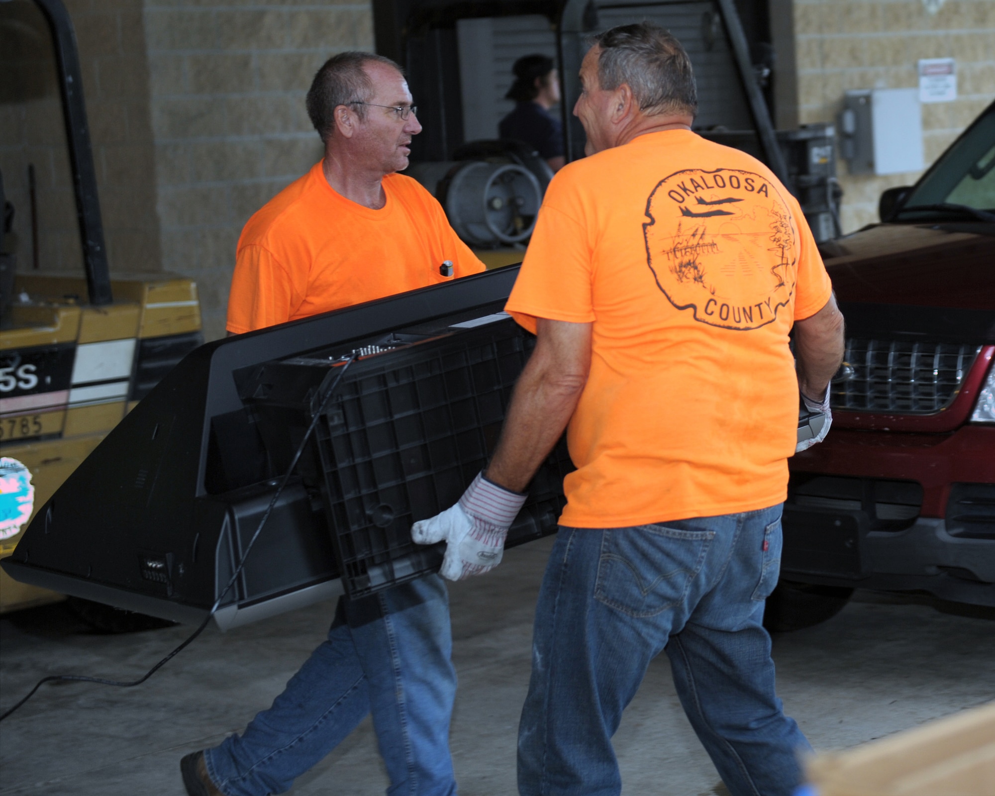 Darryl Roper, left, Okaloosa County Hazardous Waste recycling foreman, and John Hamlett, right, Okaloosa County senior groundkeeper, carry a TV to a recycling bin during a Household Hazardous Waste Collection Day at Hurlburt Field, Fla., Oct. 18, 2013. Hurlburt residents and employess dropped off various household items during the event including oil and paint. (U.S. Air Force photo/Senior Airman Kentavist P. Brackin)