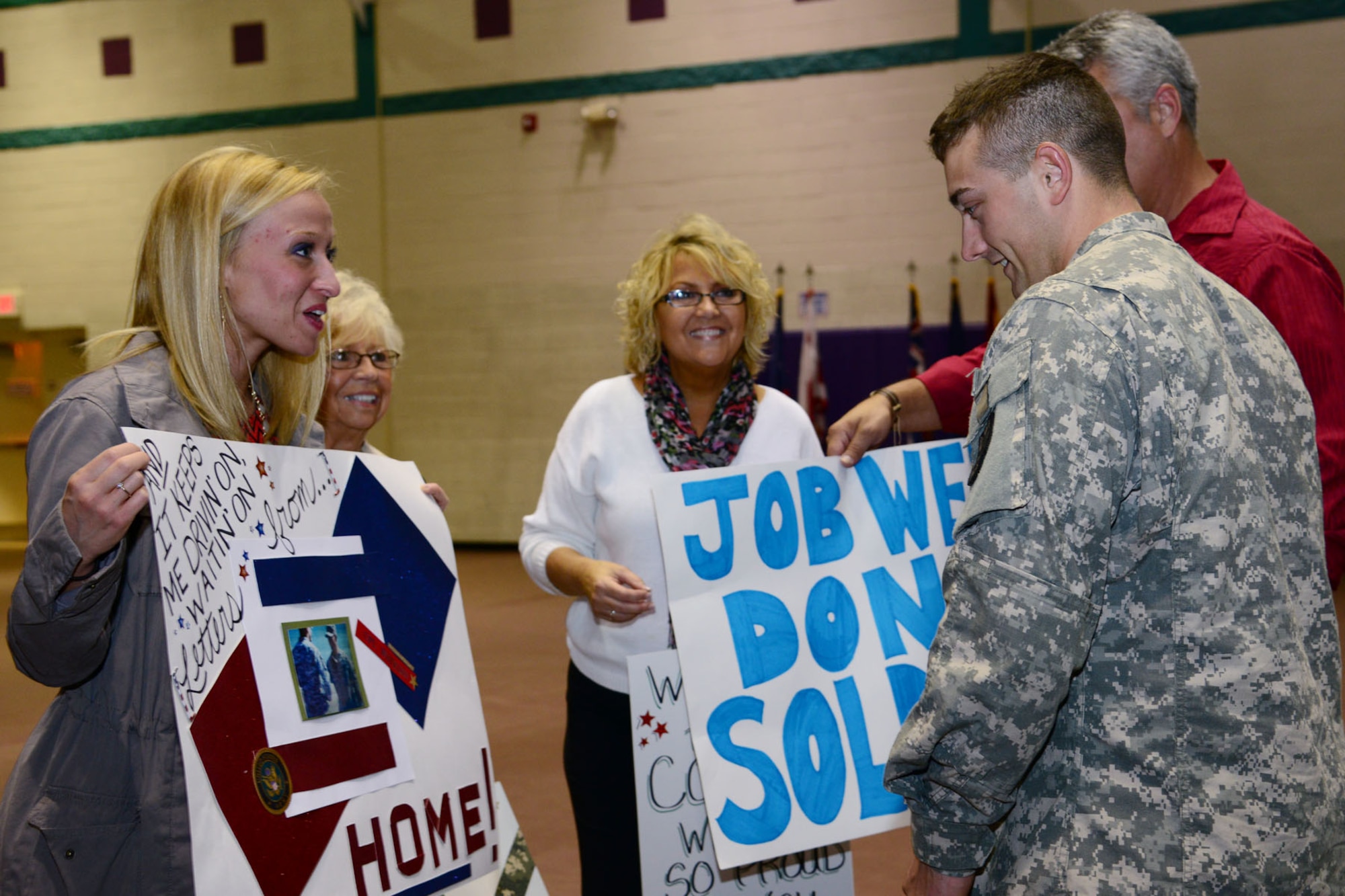 U.S. Army Cpl. Colton Watkins, 393rd Harbor Master Detachment, 10th Battalion, 7th Sustainment Brigade watercraft operator’s family display homemade signs during a redeployment ceremony at the McClellan Fitness Center, Fort Eustis, Va., Oct. 21, 2013. Soldiers with the 393rd Harbor Master Det. were responsible for conducting harbormaster operations in support of all Army watercraft, at Kuwait Naval Base, Kuwait during a nine-month deployment. (U.S. Air Force photo by Staff Sgt. Ashley Hawkins/Released)