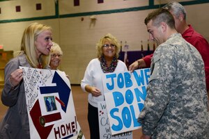 U.S. Army Cpl. Colton Watkins, 393rd Harbor Master Detachment, 10th Battalion, 7th Sustainment Brigade watercraft operator’s family display homemade signs during a redeployment ceremony at the McClellan Fitness Center, Fort Eustis, Va., Oct. 21, 2013. Soldiers with the 393rd Harbor Master Det. were responsible for conducting harbormaster operations in support of all Army watercraft, at Kuwait Naval Base, Kuwait during a nine-month deployment. (U.S. Air Force photo by Staff Sgt. Ashley Hawkins/Released)