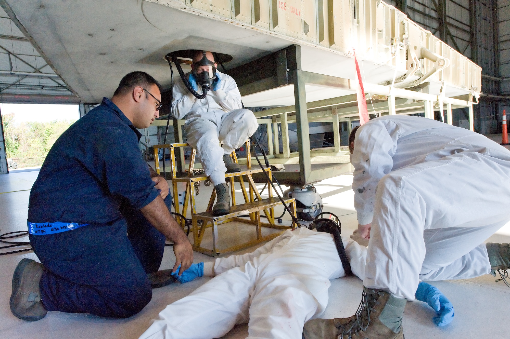 Simulated victim Airman 1st Class Joshua Lamontagne, is attended to by Staff Sgt. Lemuel Robledo, left, and Senior Airman Jason Morton, right, all from the 436th MXS, Oct. 18, 2013, at Dover Air Force Base, Del. Senior Airman Brandon Reeves, top, extracted Lamontagne from the C-5A fuel tank trainer during a confined-space rescue exercise. (U.S. Air Force photo/Roland Balik)
