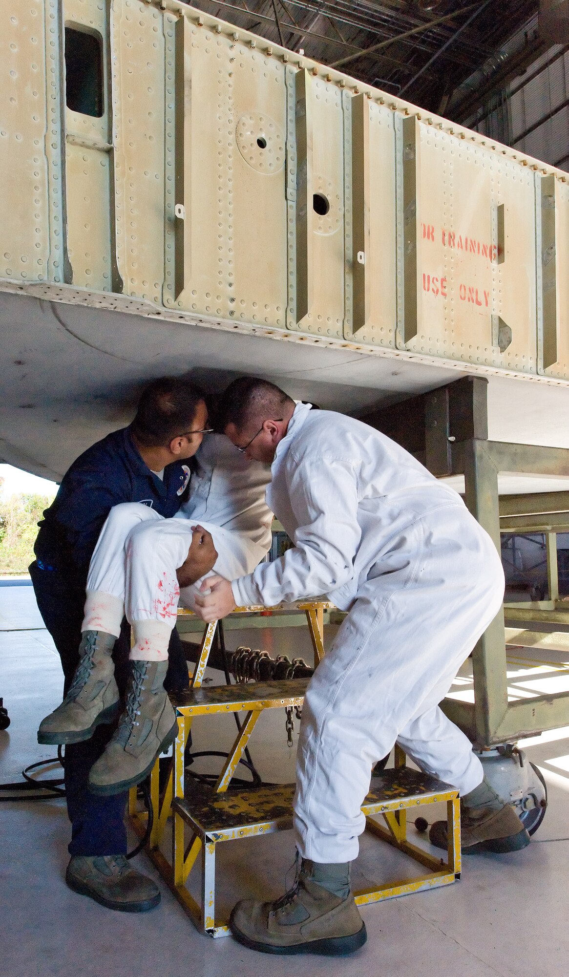 Simulated victim Airman 1st Class Joshua Lamontagne, center, 436th Maintenance Squadron, is lowered from the fuel tank access point Oct. 18, 2013, during a confined-space rescue training exercise at Dover Air Force Base, Del. Staff Sgt. Lemuel Robledo, left, and Senior Airman Jason Morton, right, both from the 436th MXS, removed Lamontagne and provided self-aid buddy care prior to the arrival of first responders. (U.S. Air Force photo/Roland Balik)
