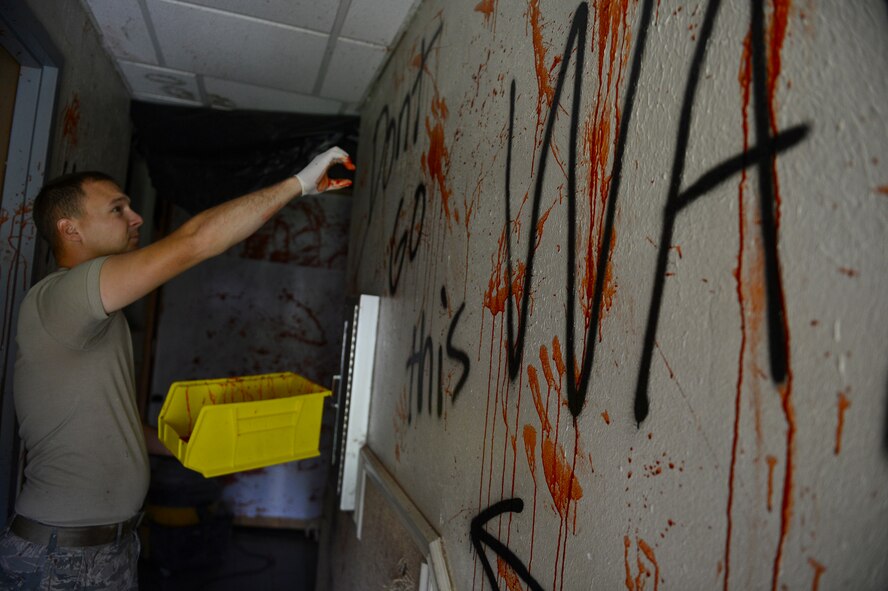 Staff Sgt. Thomas Zweydoff, 2nd Civil Engineer Squadron utilities craftsman, decorates a wall with fake blood at the old Security Forces Confinement Facility on Barksdale Air Force Base, La., Oct. 22, 2013. Zweydoff decorated the facility for the annual CE Haunted House. Fake blood can be made from scratch by using corn syrup, red dye, water and cornstarch. (U.S. Air Force photo Senior Airman Micaiah Anthony)