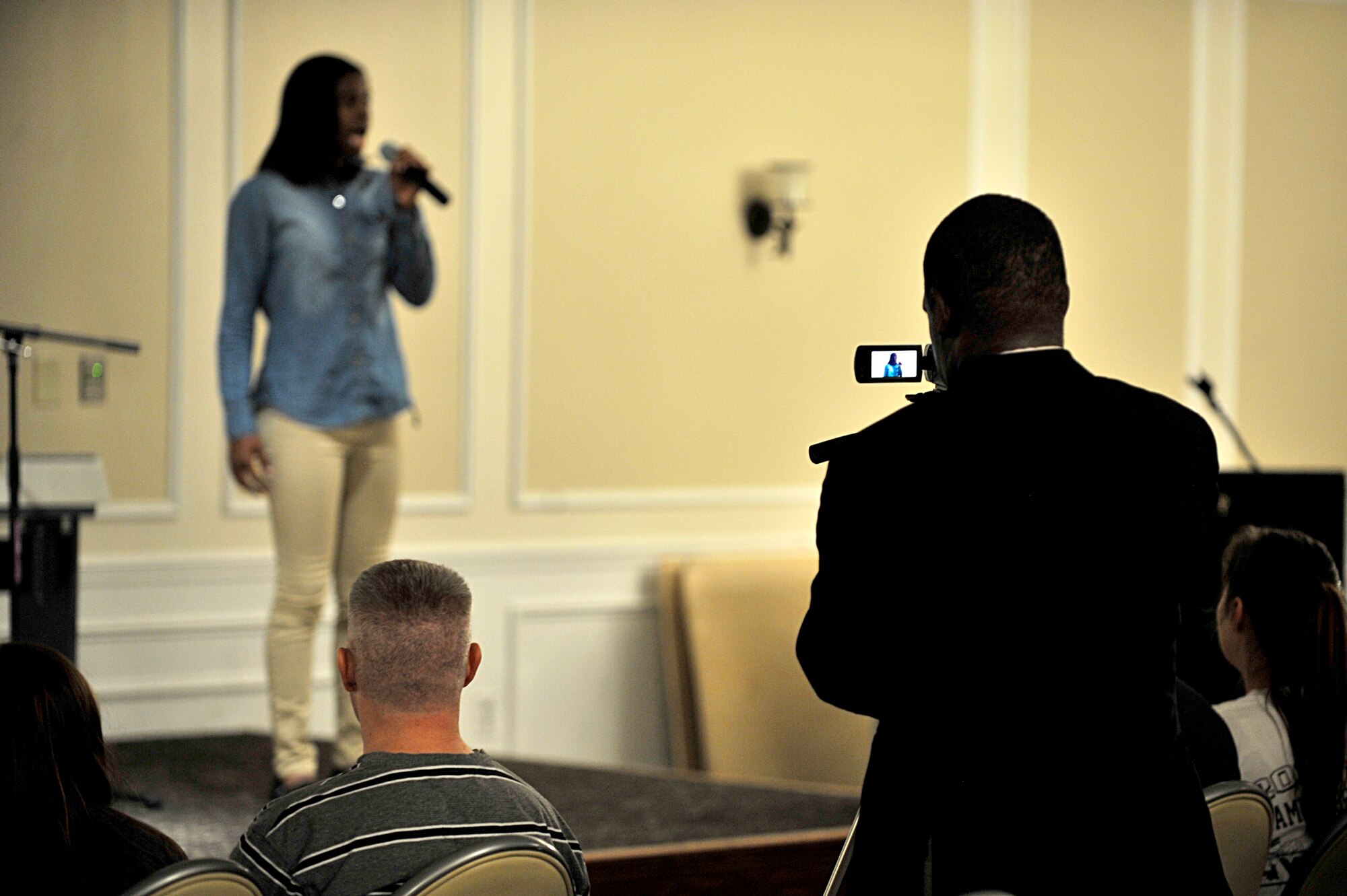 [From right] Derrick Rhems, 20th Force Support Squadron marketing and promotions director, records Aaliyah Johnson, daughter of Staff Sgt. Voncille Whigum, AFCENT, during a “U Got Talent” competition, Oct. 17, 2013, at Shaw Air Force Base, S.C.. The base-level competition was held for performers to showcase their talent and compete to perform in the Air Force-level competition which will begin in December. (U.S. Air Force photo by Airman 1st Class Jensen Stidham/Released) 