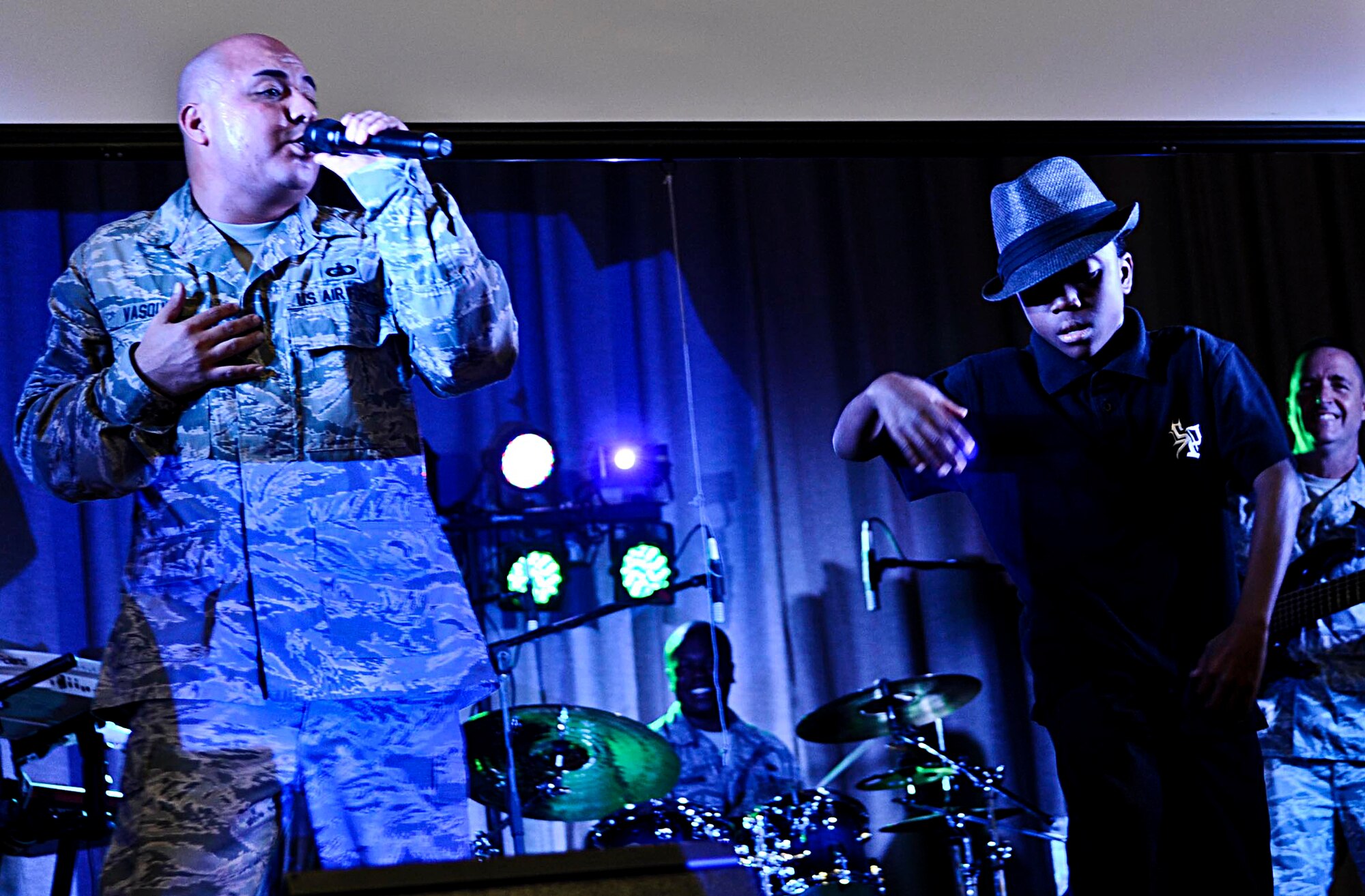U.S. Air Force Tech. Sgt. Richard Vasquez, U.S. Air Force Heritage of America band rock ensemble vocalist, performs while Dominique, an Armstrong Elementary School student, dances alongside the band in Hampton, Va., Oct. 18, 2013. In April 2013, the students gave the band pictures and hand-made cards to present to Kyrgyzstani children while the band was deployed to Asia. (U.S. Air Force photo by Airman 1st Class R. Alex Durbin/Released)