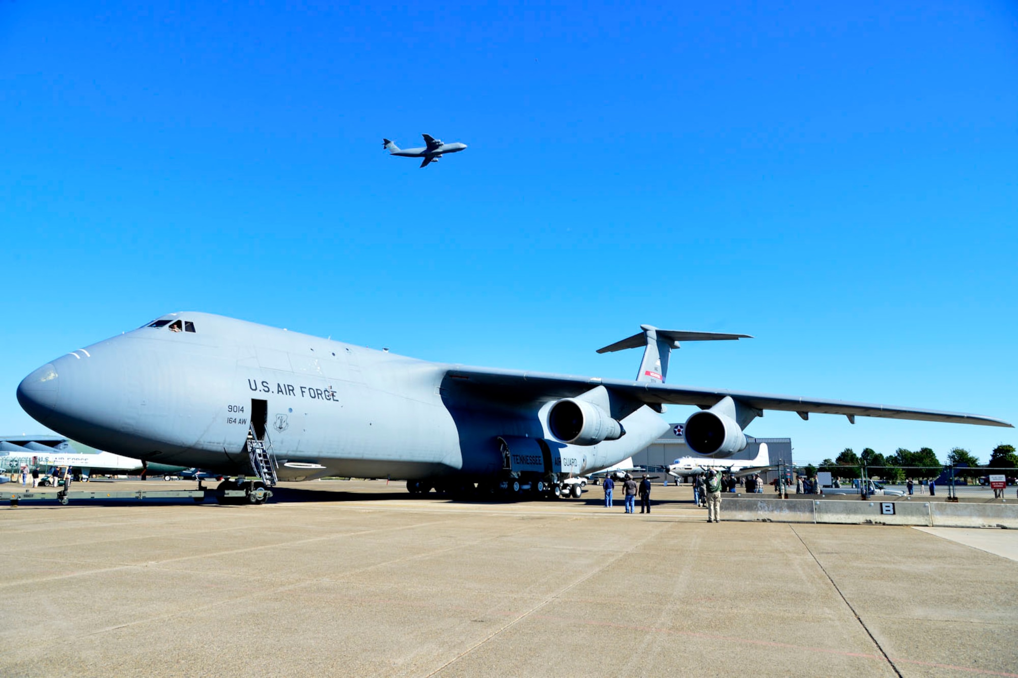 The new C-5A Galaxy sits in its new spot as a C-5M Super Galaxy flies overhead Oct. 21, 2013, at the Air Mobility Command Museum on Dover Air Force Base, Del. This particular aircraft was last assigned to the Tennessee Air National Guard’s 164th Airlift Wing in Memphis Tennessee, and is known for its successful  launch of a 56-foot long, 86,000 pound  Minuteman Intercontinental Ballistic Missile over the Pacific Ocean.  (U.S. Air Force photo/David Tucker)