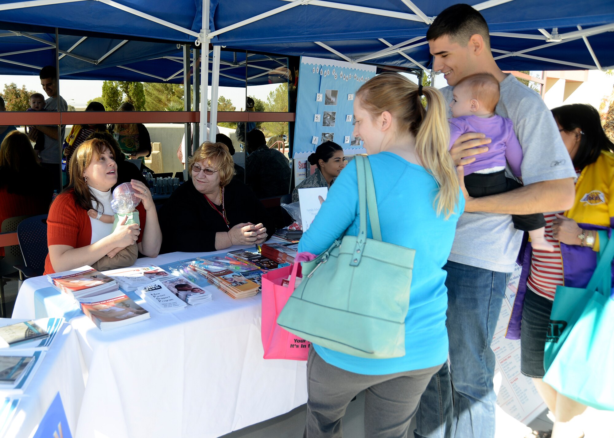 An Edwards family visits the New Parent's Support Program desk and display at the 412th Medical Group Health Fair Oct. 17. The health promotion event gave visitors the chance to pick up information on health and also featured services provided by off base health facilities. The event lasted from 10 a.m. to 2 p.m. (U.S. Air Force photo by Kenji Thuloweit)