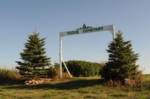 The entryway to the Tagus, N.D., cemetery stands between two pines at the top of a hill. The cemetery once contained a church which burnt down in 2001 and is now remembered with a small marker over the location it once stood. (U.S. Air Force photo/Senior Airman Stephanie Sauberan)
