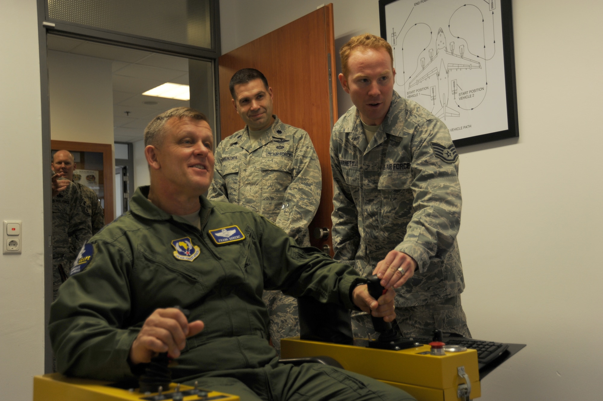 SPANGDAHLEM AIR BASE, Germany --- Gen. Frank Gorenc, U.S. Air Forces in Europe and Air Forces Africa commander, seated left, learns to operate a deicing simulator from Staff Sgt. Jesse Garnett, 726th Air Mobility Squadron technician, as Lt. Col. Chad Annunziata, 726th AMS commander, looks on during a tour Oct. 18, 2013. Both the general and Chief Master Sgt. James Davis, USAFE and AF Africa command chief, used the simulator as part of their tour. (U.S. Air Force photo by Senior Airman Joe W. McFadden / Released)