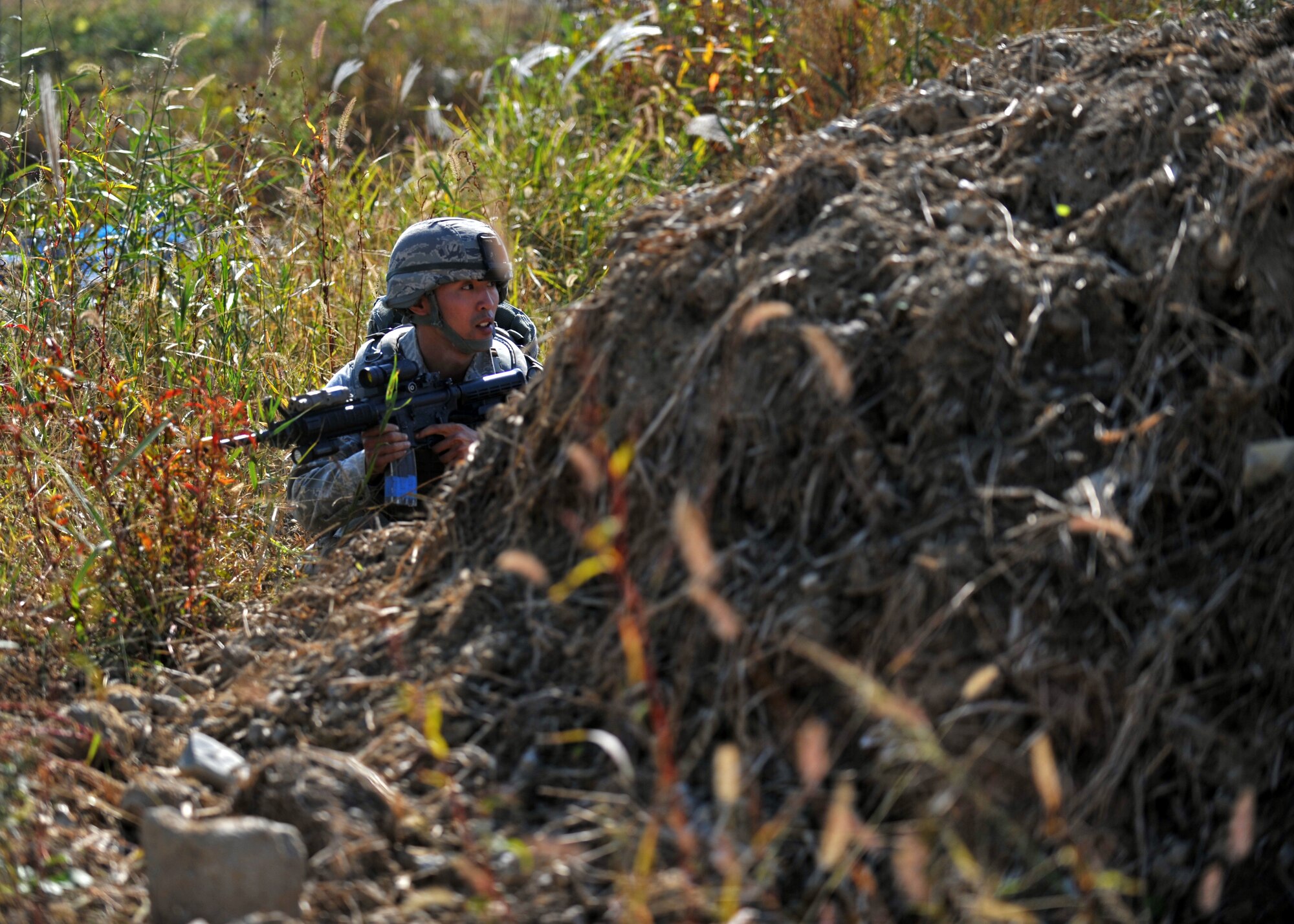 Senior Airman Hong Dick Li, 51st Security Forces Squadron fire team member, takes cover during a field training exercise near the perimeter of Osan Air Base, Republic of Korea, Oct. 18, 2013. Li and his fire team were dispatched after receiving intelligence that opposition forces were planning to infiltrate the base. (U.S. Air Force photo/Senior Airman Siuta B. Ika)
