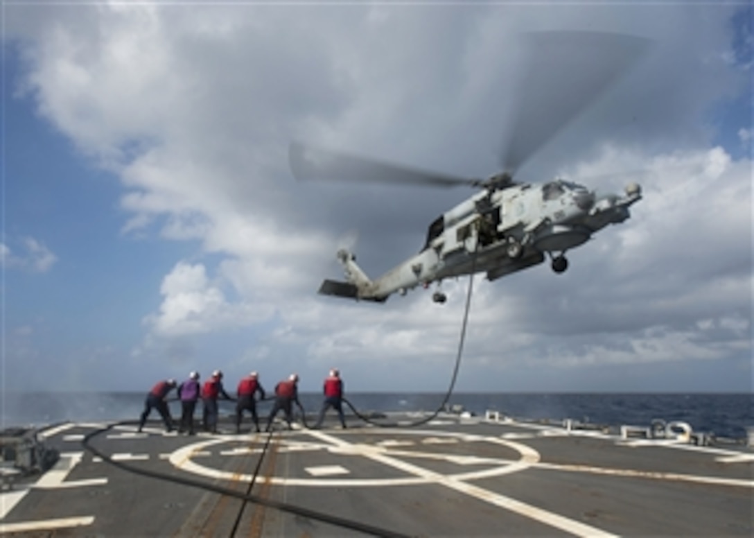 U.S. Navy sailors tend a fuel hose for an inflight refueling of an MH-60R Seahawk helicopter from the flight deck of the guided-missile destroyer USS Mustin (DDG 89) as the ship operates in the South China Sea on Oct. 20, 2013.  The Mustin is deployed to the U.S. 7th Fleet area of responsibility to conduct maritime security operations and theater security cooperation efforts.  The Seahawk is attached to Helicopter Maritime Strike Squadron 51.  