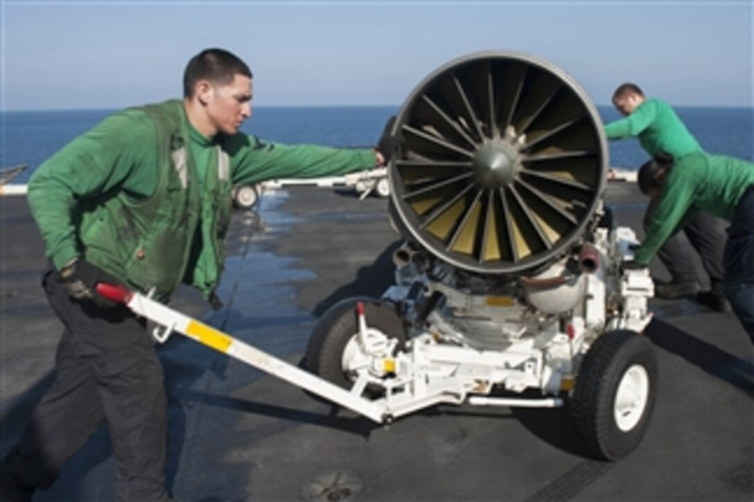 U.S. Navy Petty Officer 3rd Class Enoc Silva uses the tow bar to steer the cart as they move an F/A-18E Super Hornet engine on the flight deck of the aircraft carrier USS Harry S. Truman (CVN 75) while the ship operates in the Gulf of Oman on Oct. 20, 2013.  The Truman Carrier Strike Group is deployed to the U.S. 5th Fleet area of responsibility to conduct maritime security operations and theater security cooperation efforts.  