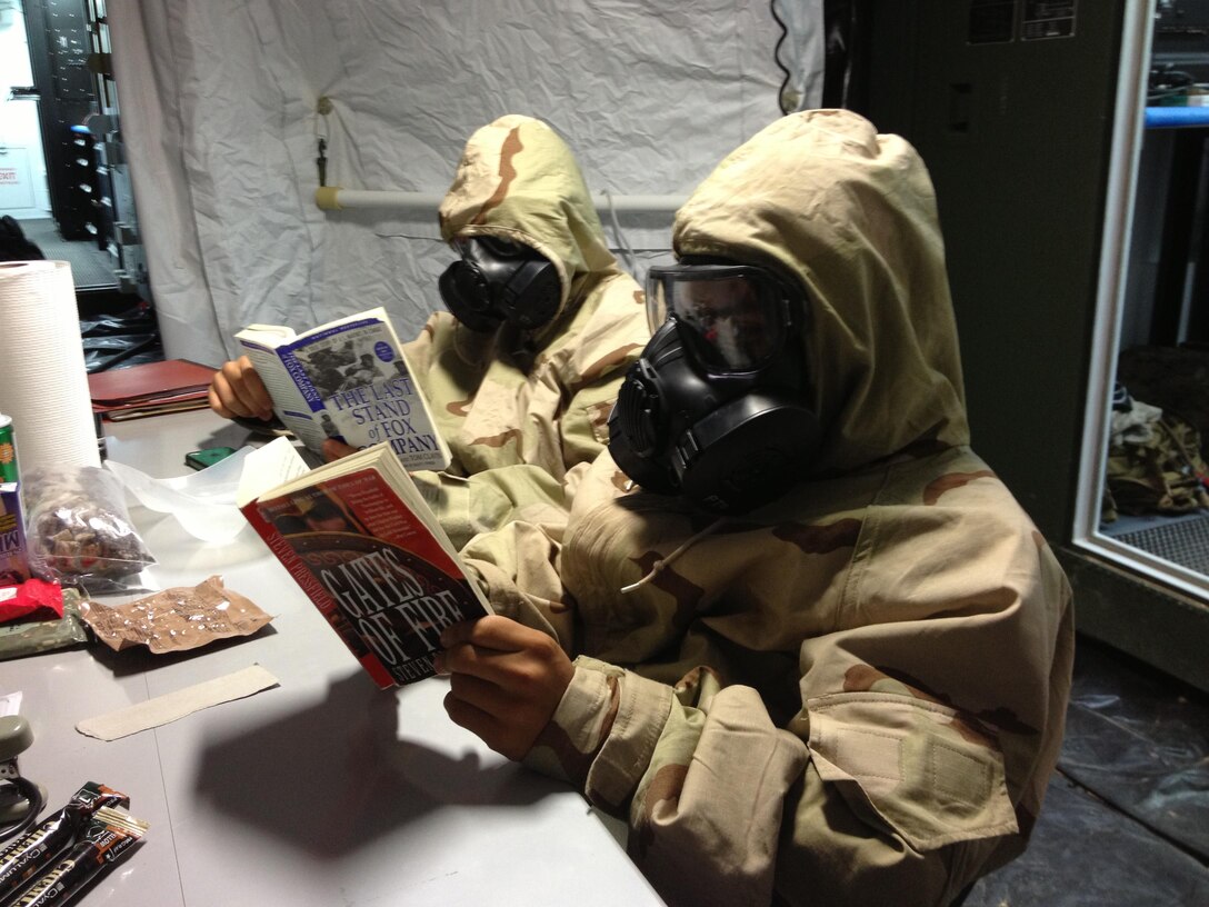 Marines practice their mission-oriented protective posture suit training during the 3rd Maintenance Battalion Field Exercise 13-2 in the Central Training Area of Okinawa, Japan September 11, 2013.  They took a lunch break in their MOPP suits while reading books from the Commandant’s professional reading list and embodying the whole Marine concept. Chemical, biological, radiological and nuclear training is often overlooked when units go to the field; however, 3rd Maintenance Battalion’s training ensures the Marines are prepared to perform all daily maintenance operations while at various MOPP levels. The Marines are with 3rd Maintenance Battalion, Combat Logistics Regiment 35, 3rd Marine Logistics Group, III Marine Expeditionary Force.