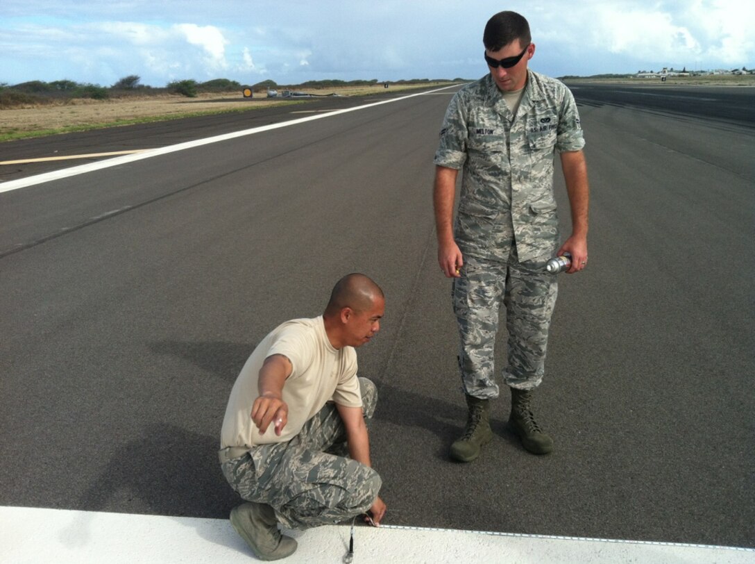 Staff Sgt. Orlando Crespo (kneeling), and Airman 1st Class Christopher Melton, both from the 647th Civil Engineer Squadron Structures Flight, verify the accuracy of layout markings before painting the first-ever assault landing zone at the Navy’s Barking Sands Pacific Missile Range Facility on the island of Kauai. Due to the teamwork from PMRF leadership and the 647th CES Airmen, the PMRF runway will now also serve as a temporary ALZ for the active-duty 535th and the Air National Guard’s 204th C-17 Airlift Squadrons. (Courtesy photo)