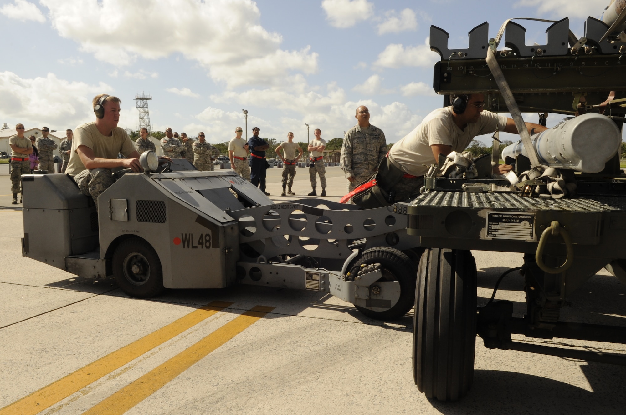 U.S. Air Force Airman 1st Class Zachary Ross guides a bomb loader into place as Staff Sgt. Emad Hamedeyyeh straps a missile onto it during a quarterly weapons load competition at Kadena Air Base, Japan, Oct. 18, 2013. The 67th AMU beat the 44th Aircraft Maintenance Unit by being the quickest team to load weapons onto an F-15 Eagle with the fewest errors. Both Ross and Hamedeyyeh are 67th Aircraft Maintenance Unit weapons load crew members. (U.S. Air Force photo by Senior Airman Marcus Morris) 