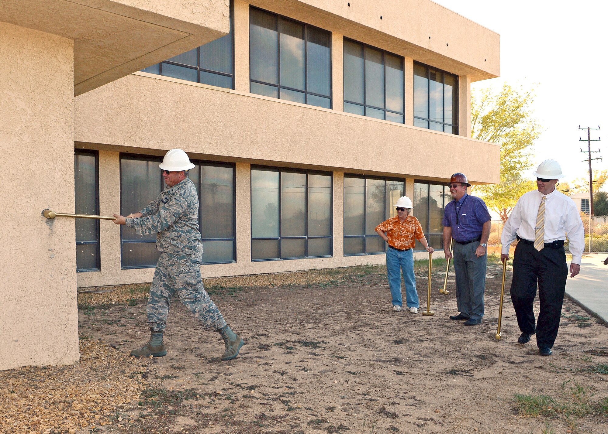 Brig. Gen. Michael Brewer (left), 412th Test Wing commander, swings a ceremonial sledge hammer Oct. 22 to officially begin the demolition of Building 2650A, the former home of the Edwards AFB Environmental Management Branch. Of those in attendance, James Judkins, 412th Civil Engineer Division director, Dick Burr of BURR-MZT (the contractor whose company is accomplishing the demolition of B2650A and the improvements to B3735, B4900 and B4904), John Stephens, Army Corps of Engineers director at Edwards, Herb Rorabach, Environmental Management director, and Pamela Birge, a 412th CE security manager who was an original occupant of the building, all took turns taking swings at the building. (U.S. Air Force photo by Jet Fabara)