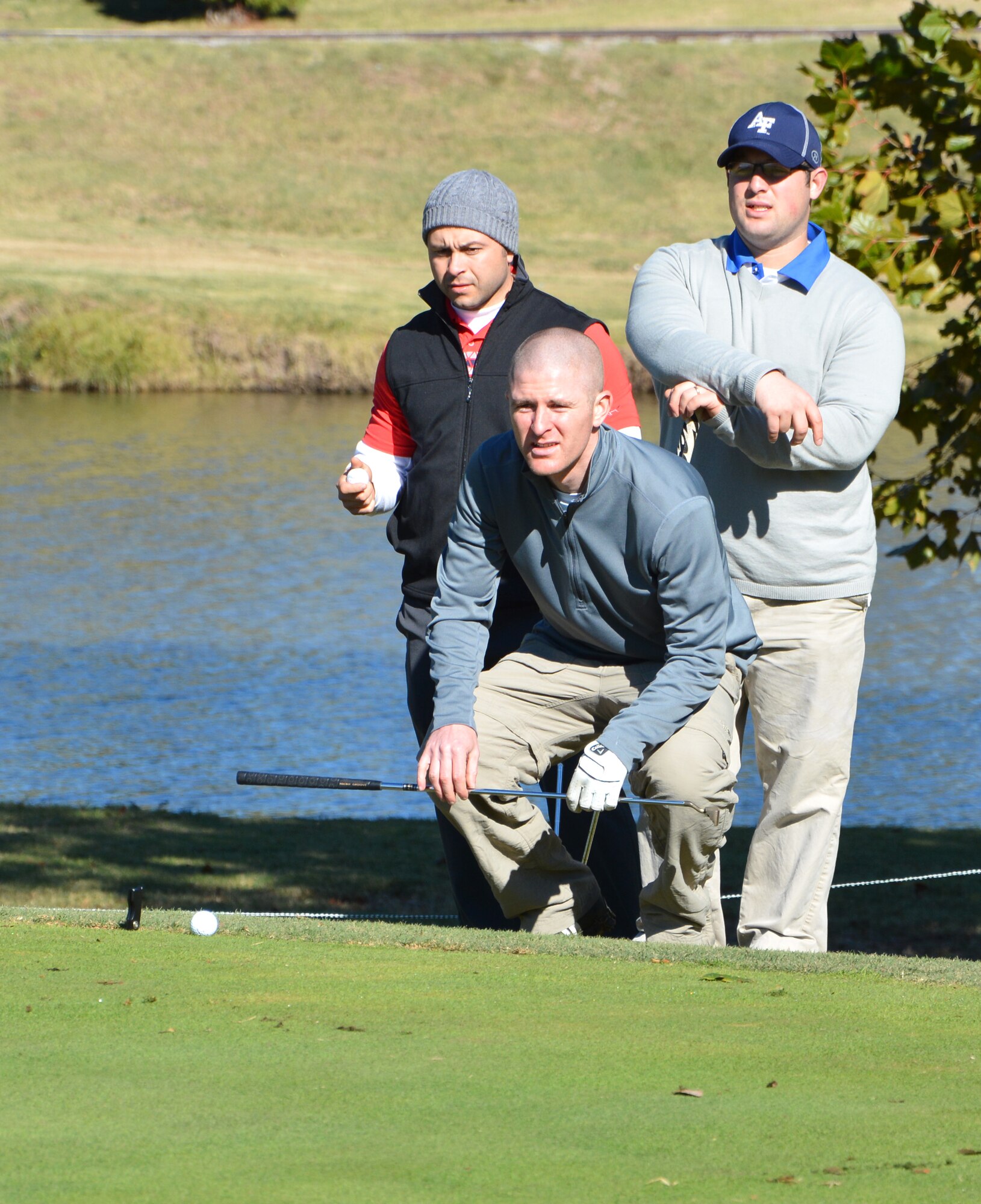While 2nd Lt. Mike Cosand lines up his putt, his teammates, Maj. Matt Portno, left, and 2nd Lt. Scott Brooks, maintain positive attitudes during the 2013 Combined Federal Campaign golf tournament, held Oct. 19 at Meadowlake Golf Course. (Courtesy photo)