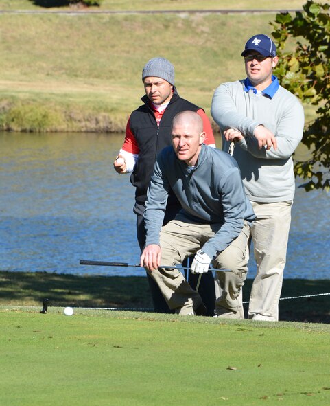 While 2nd Lt. Mike Cosand lines up his putt, his teammates, Maj. Matt Portno, left, and 2nd Lt. Scott Brooks, maintain positive attitudes during the 2013 Combined Federal Campaign golf tournament, held Oct. 19 at Meadowlake Golf Course. (Courtesy photo)