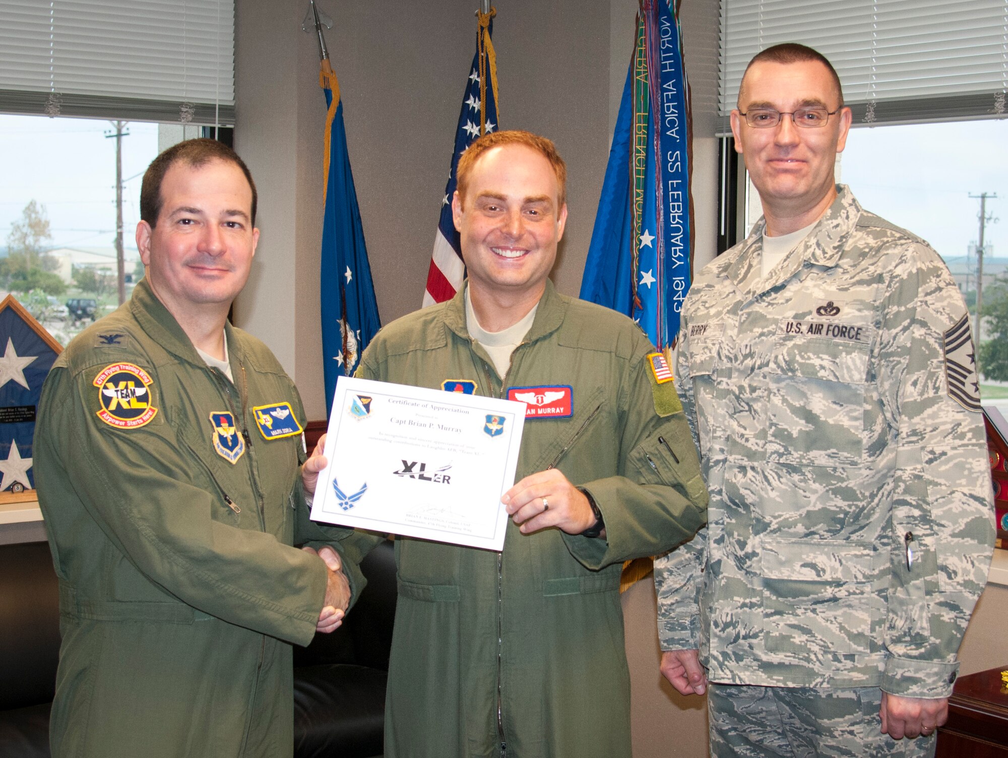 Capt. Brian Murray, 47th Medical Operation Squadron flight surgeon, poses with Col. Mark Doria, 47th Flying Training Wing vice commander, and Chief Master Sgt. Garry Berry, 47th FTW command chief, after being presented the XLer of the week award here Oct. 21, 2013. The XLer is a weekly award chosen by wing leadership and given to those who consistently make outstanding contributions to Laughlin and their unit. (U.S. Air Force photo/George McKnight)