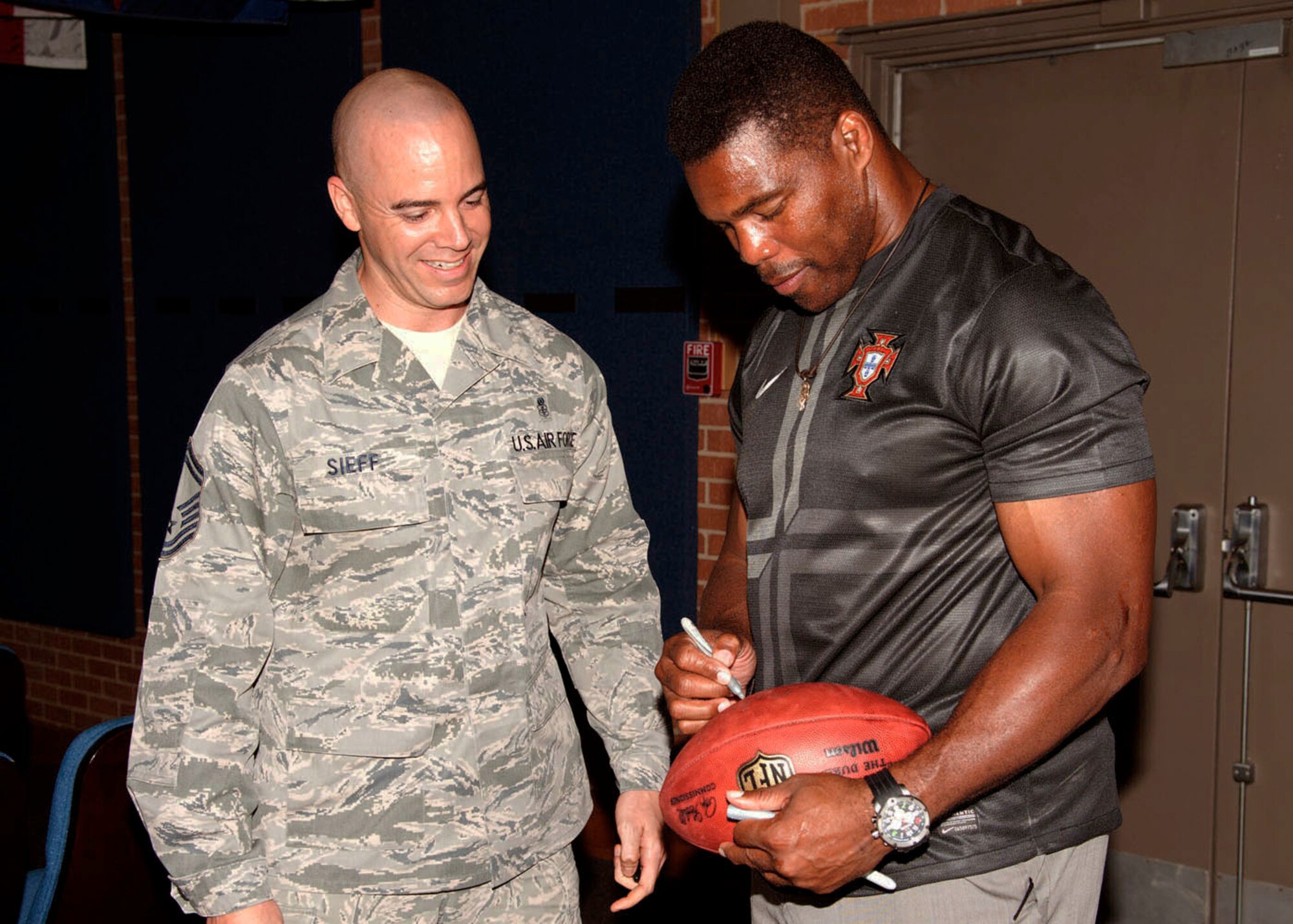 Herschel Walker signs an autograph for Senior Master Sgt. Oren Sieff, 59th Surgical Operations Squadron Superintendant, Oct. 23, 2013 in the Wilford Hall Ambulatory Surgical Center auditorium, Joint Base San Antonio-Lackland, Texas. (U.S. Air Force photo/Senior Airman Chelsea Browning)