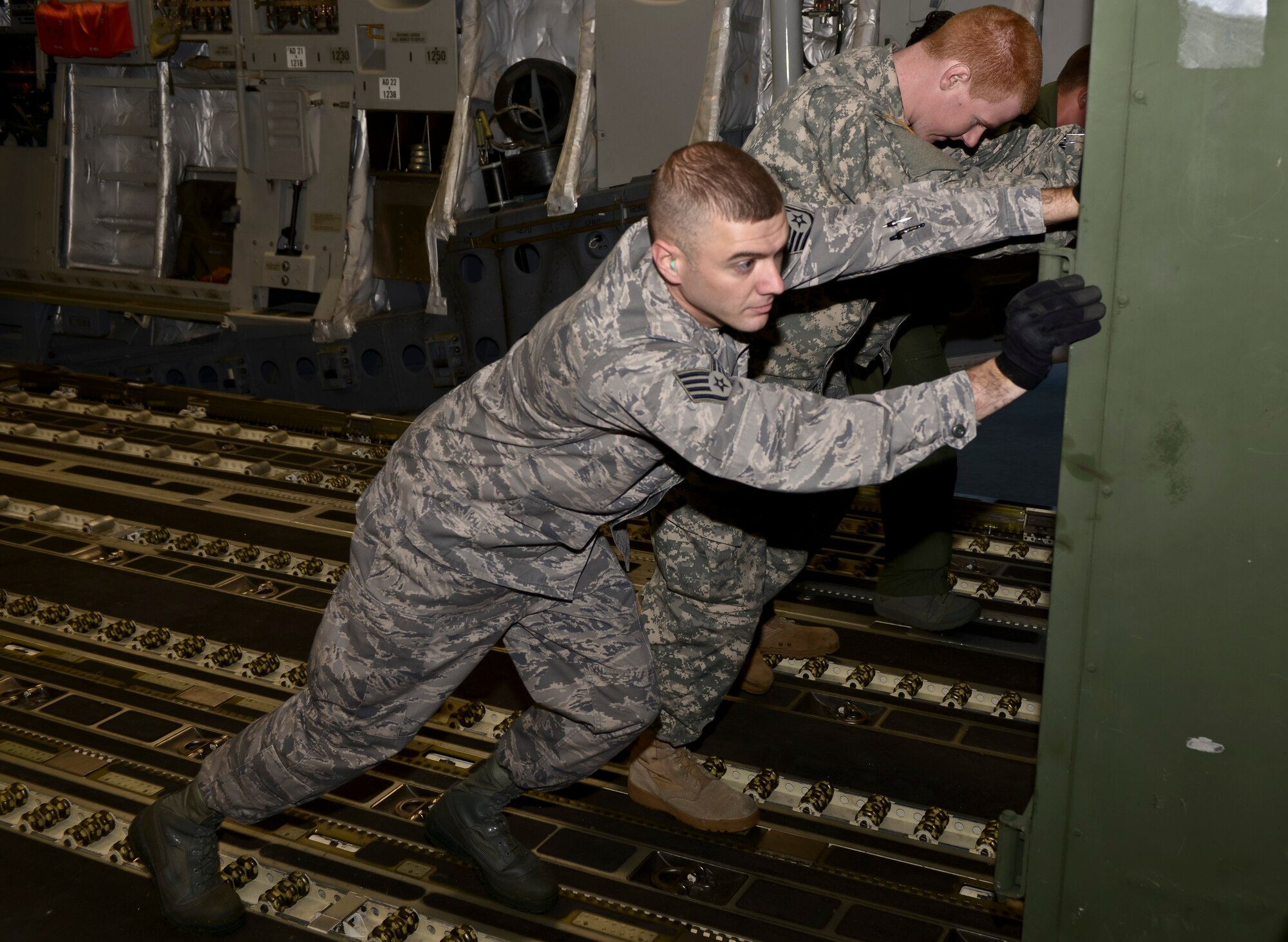 U.S. Air Force Staff Sgt. Andrew Hughes, 633rd Logistics Readiness Squadron air terminal supervisor, assists U.S. Army personnel push a container out of a C-17 Globemaster III at Langley Air Force Base, Va., Oct. 23, 2013. Huges helped train Soldiers from the 622nd Movement Control Team, Army Departure Airfield Control Group, from Fort Eustis, Va., gain large airframe training unloading cargo from the redeployment of the 27th Fighter Squadron. (U.S. Air Force photo by Senior Airman Connor Estes/Released)