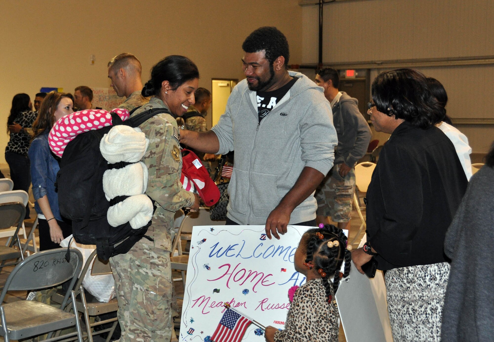 NELLIS AIR FORCE BASE, Nev. -- (Left) Senior Airman Meaghan Russell, 555th RED HORSE Squadron, is welcomed home to Nellis Air Force Base, Nev., Oct. 22 by her family after a six-month deployment to Southwest Asia. The squadron deployed more than 30 members to various locations in the region where they repostured and dispositioned assets, and closed down camp sites, among other retrograde efforts. Rapid Engineer Deployable Heavy Operational Repair Squadron Engineers provide a mobile, self-sufficient force responsible for heavy repair and construction in remote environments. (U.S. Air Force photo/Maj. Jessica Martin)