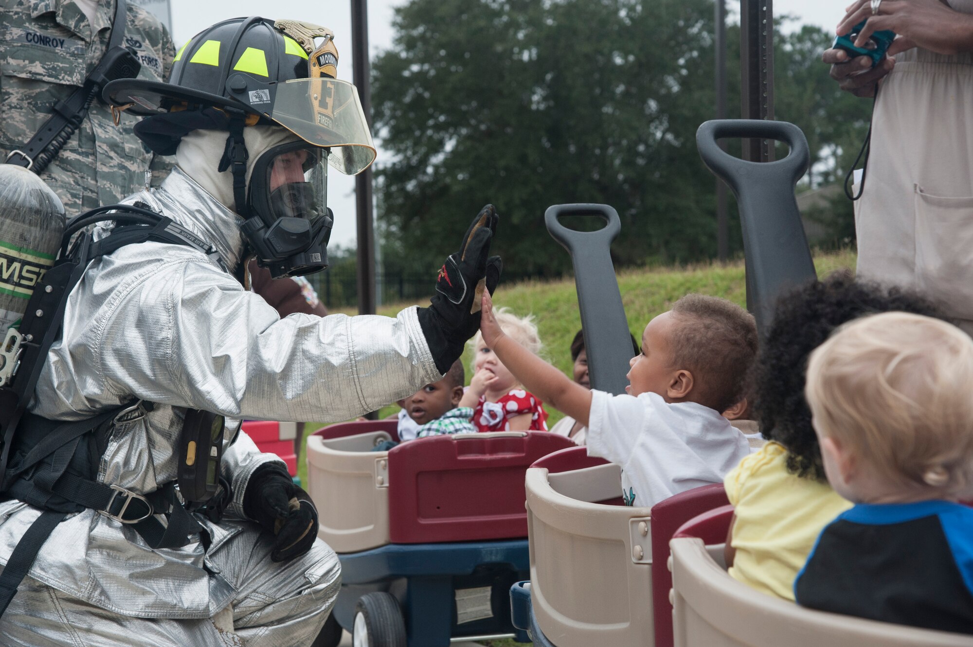 U.S. Air Force Airman 1st Class Shawn Wright, 23d Civil Engineer Squadron firefighter, demonstrates to children how to put on a U.S. Air Force fire proximity suit at the Child Development Center at Moody Air Force Base, Ga., Oct. 9, 2013. The fire proximity suit is made of material meant to reflect the heat emitted from high-temperature flames. (U.S. Air Force photo by Airman Dillian Bamman/Released)