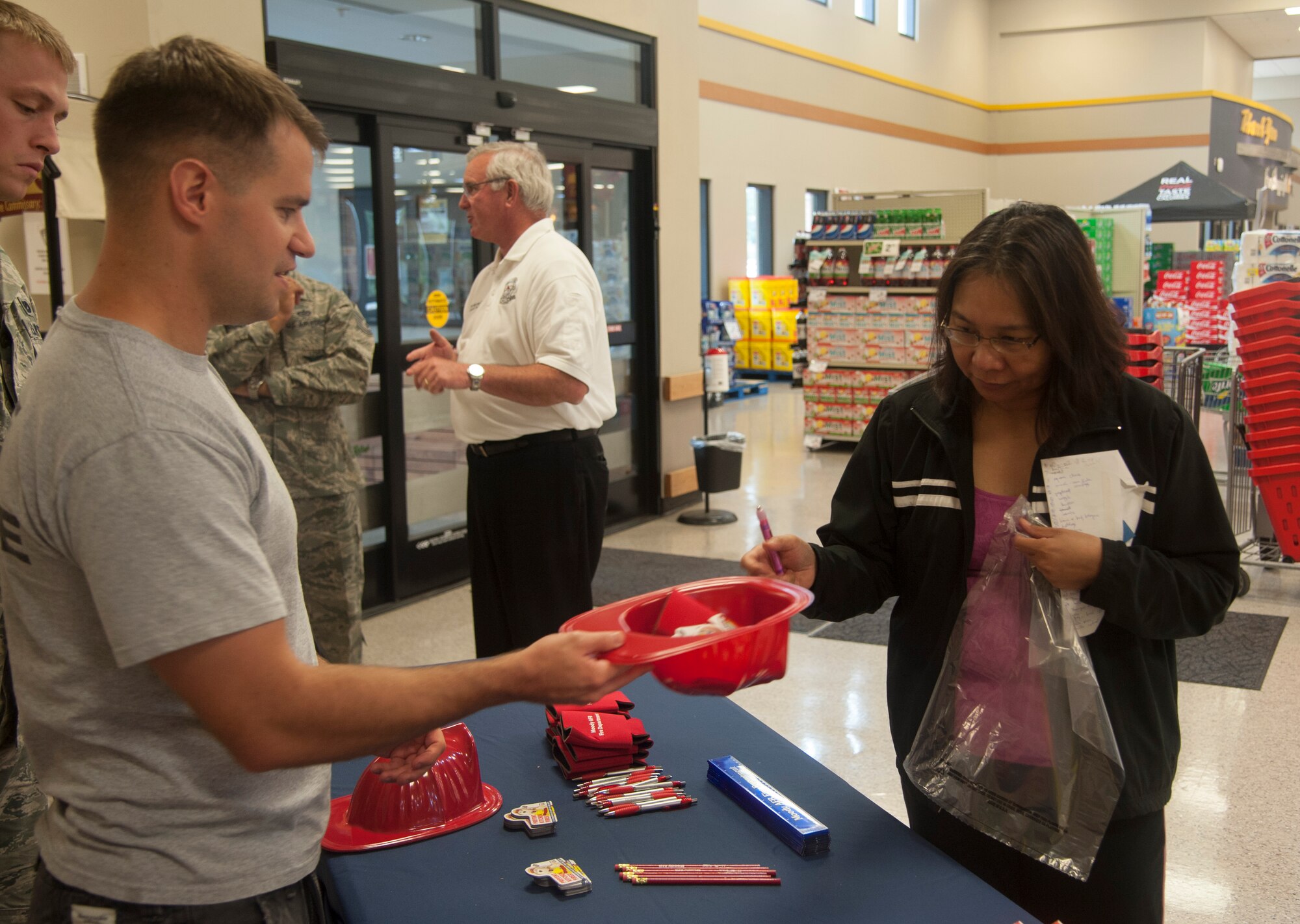 U.S. Air Force Staff Sgt. Jordan Gren, 23d Civil Engineer Squadron firefighter, speaks to a customer about preventing kitchen fires at the commissary on Moody Air Force Base, Ga., Oct. 8, 2013. Fire Prevention Week is designed to raise fire safety awareness at Moody . (U.S. Air Force photo by Airman Dillian Bamman/Released)