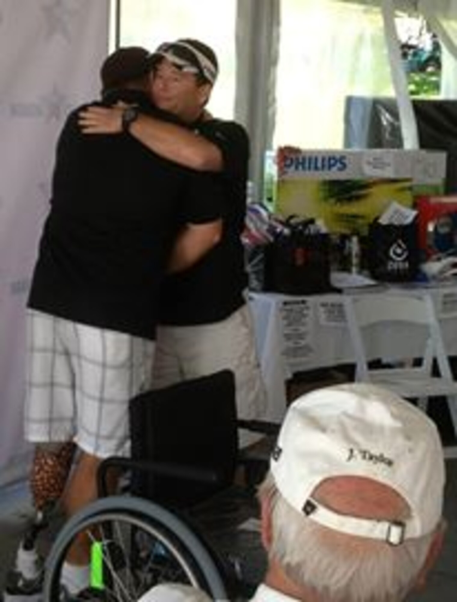 Chris Paulsen hugs Patriots Honor president, Chief Master Sergeant Brent Hammond, after Paulsen was presented with a specialized sports wheelchair that will allow the competitive bowler to participate in upcoming national tournaments for veteran amputees. Paulsen, a Navy veteran, was presented with the wheelchair during the inaugural Patriots Honor Golf Tournament in Lincoln Calif. (U.S. Air Force photo/Dana Lineback)