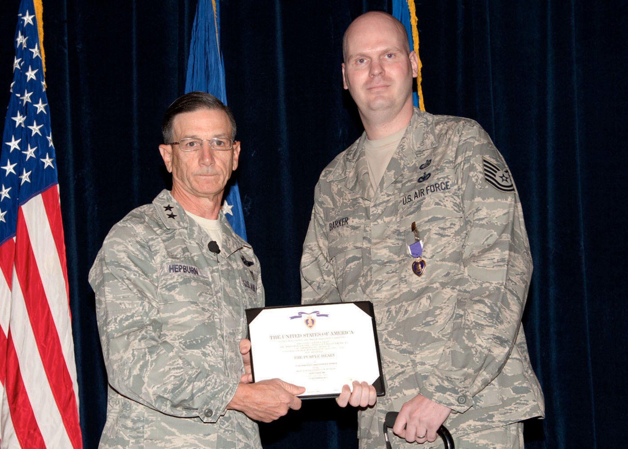 Staff Sgt. Christopher D. Barker receives the Purple Heart from Brig. Gen. Byron Hepburn, 59th Medical Wing commander, Oct. 23, 2013 in the Wilford Hall Ambulatory Surgical Center auditorium, Joint Base San Antonio-Lackland, Texas. Barker, An Air Force security forces military working dog handler now assigned to the 59th Patient Squadron, received the distinguished medal for wounds sustained while deployed to Iraq in 2006. (U.S. Air Force photo/Senior Airman Chelsea Browning)