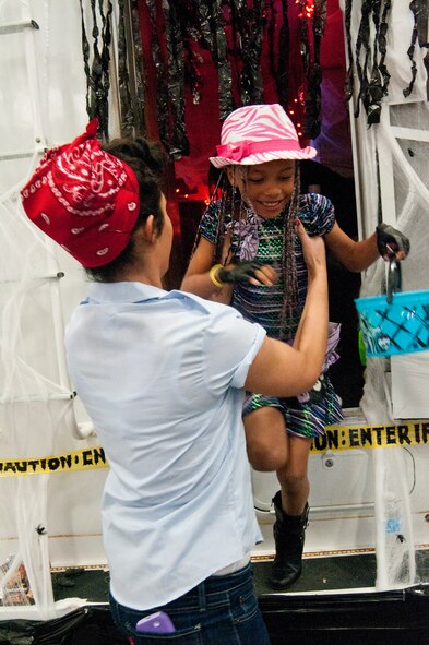 Airman 1st Class Kim Perez, 790th Missile Security Forces Squadron, helps Maalyah Haglund, niece of Tech. Sgt. Robert Haglund, 90th Security Forces Squadron, out of a 790th MSFS camper, decorated for Halloween, at the 90th Security Forces Group Trunk-or-treat in Bldg. 1501, Oct. 19, 2013. (U.S. Air Force photo by Airman 1st Class Jason Wiese)