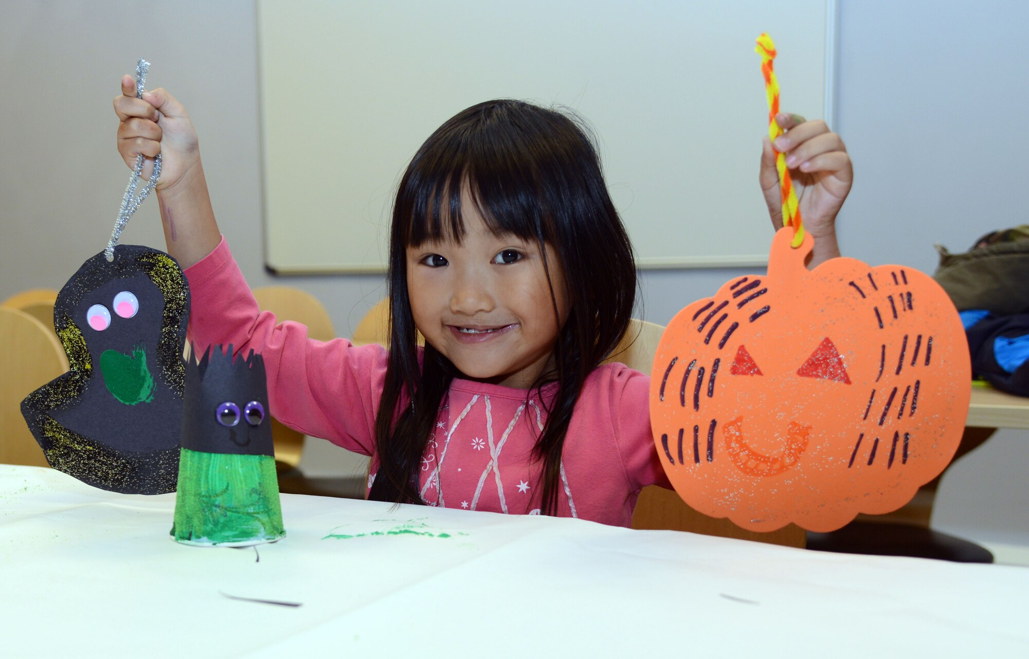 Bethany Zaleski, 5, daughter of U.S. Air Force Lt. Col. Vincent Zaleski, 95th Reconnaissance Squadron commander from Ironwood, Mich., shows off the arts and crafts she made during the Exceptional Family Member Program family bowling night Oct. 21, 2013, at the bowling center on RAF Mildenhall, England. The EFMP family bowling night is held quarterly, allowing people with exceptional family members to come together and network. The EFMP also holds a quarterly skating night as well as different support groups and consultations. (U.S. Air Force photo by Airman 1st Class Kelsey Waters/Released)