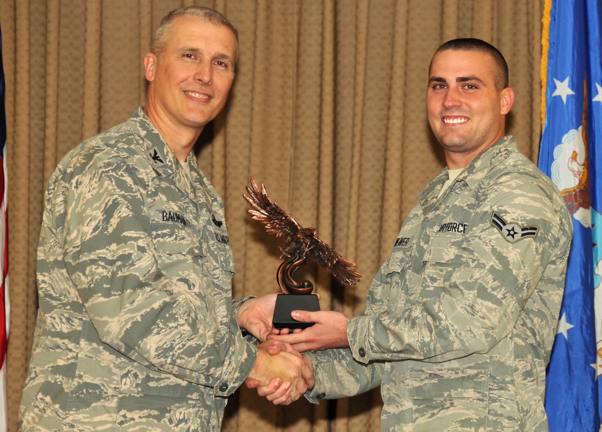 Col. Paul Bauman, 319th Air Base Wing commander, presents Airman 1st Class Joshua Weaver with the Honor Guardsman of the Quarter Award for the third quarter of 2013, during an awards ceremony on Oct. 11, 2013, at the Northern Lights Club at Grand Forks Air Force Base, N.D.  Weaver was named the base’s Warrior of the Week for the third week of October 2013. (U.S. Air Force photo/Senior Airman Xavier Navarro) (Photo was cropped to place focus on the subject in the image)