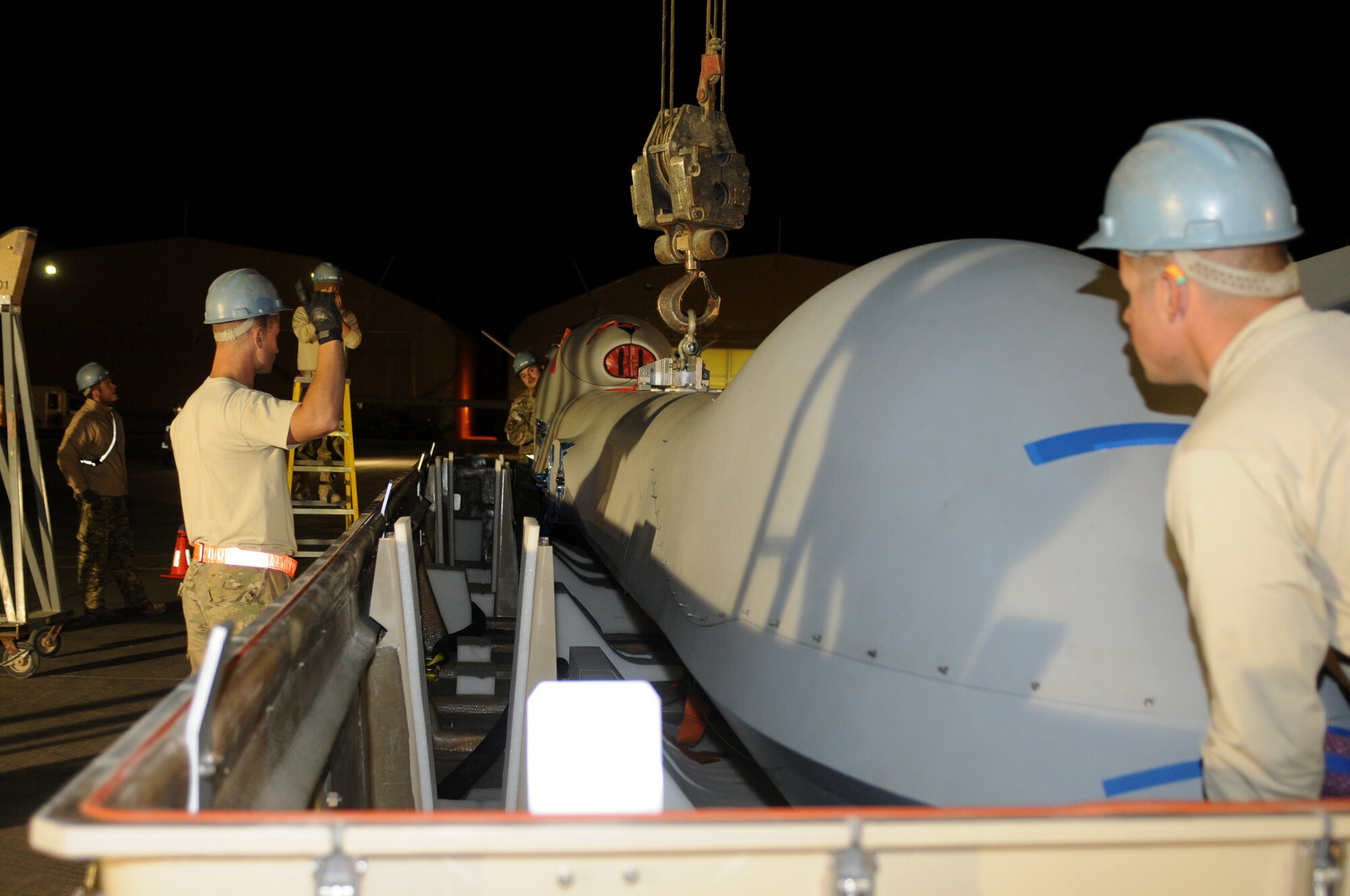 Airmen of the 451st Expeditionary Aircraft Maintenance Squadron use a crane to lift the body of an MQ-9 Reaper from a cargo container Oct. 18, 2013, at Kandahar Airfield, Afghanistan. The MQ-9’s mission is a persistent hunter-killer against emerging targets in achieving joint force commander objectives. (U.S. Air Force photo by Senior Airman Jack Sanders)