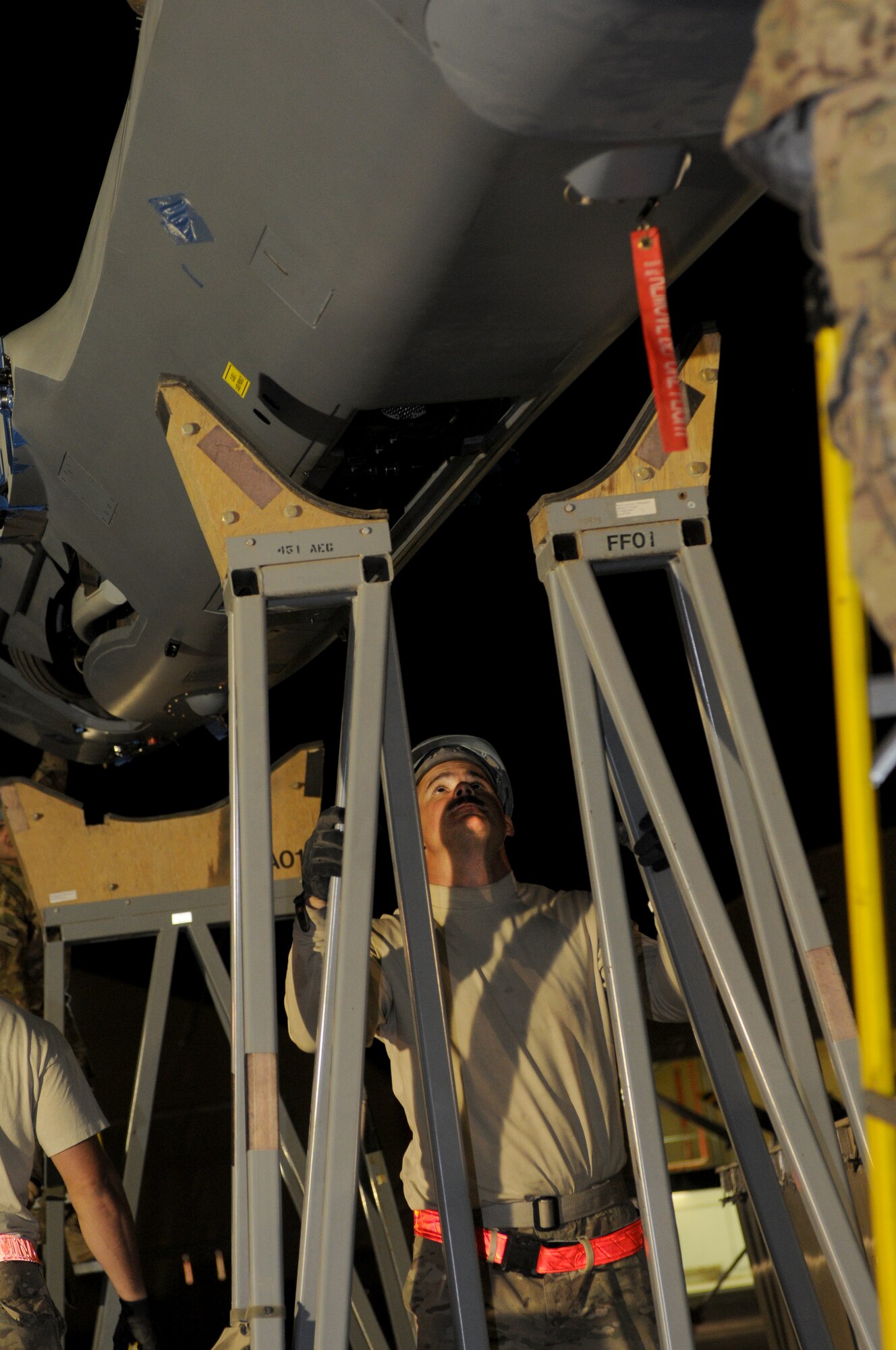 Tech. Sgt. Tyler Gruff, 451st Expeditionary Aircraft Maintenance Squadron crewchief, holds a stand as the body of an MQ-9 Reaper is lowered Oct. 18, 2013 at Kandahar Airfield, Afghanistan. The MQ-9 is being unloaded and constructed here. (U.S. Air Force photo by Senior Airman Jack Sanders)
