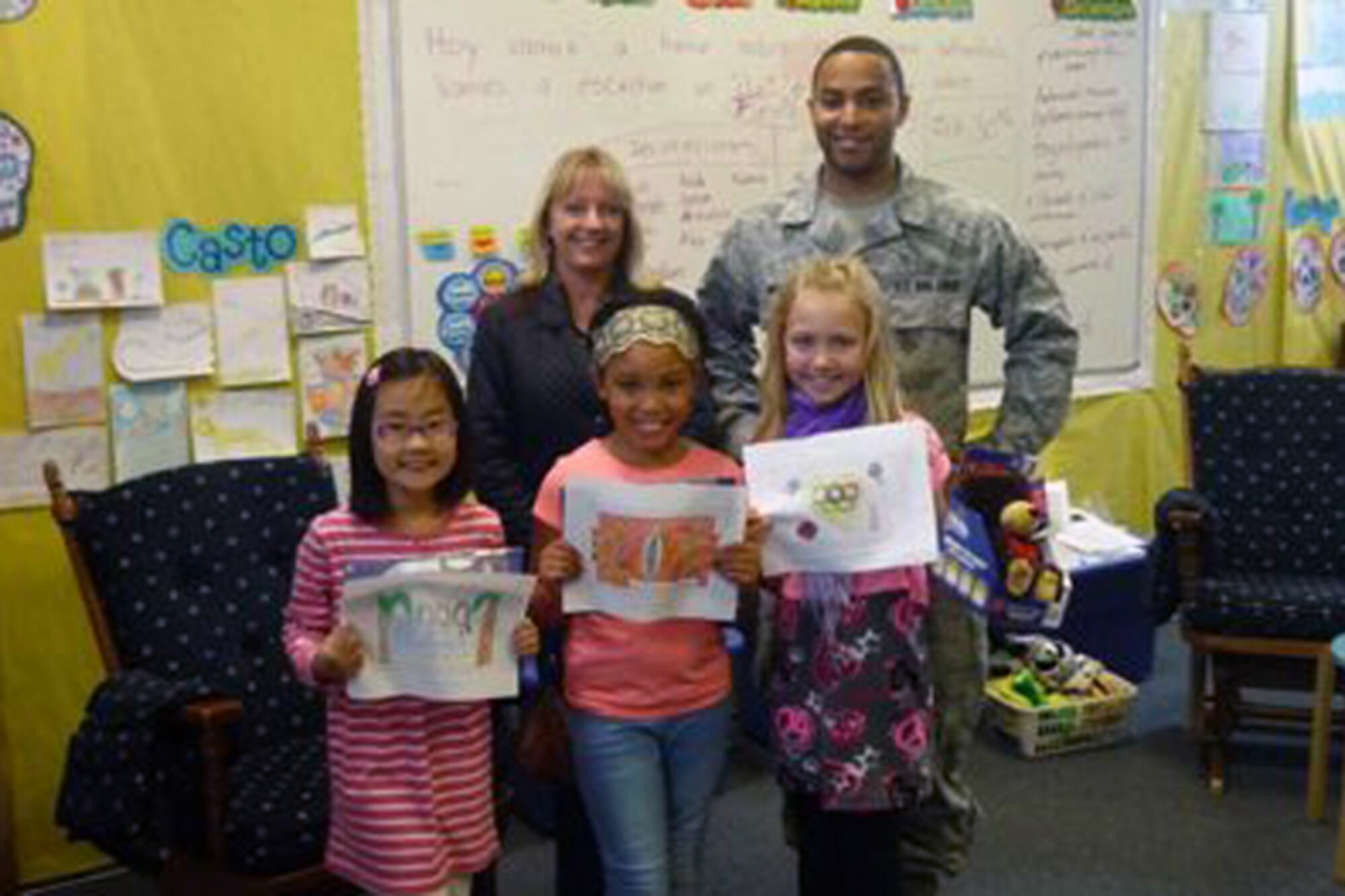 RAF ALCONBURY, United Kingdom – Senior Airman Jarron Webster and Linda Paine, both from 423rd Communications Squadron Alconbury Post Office, stand with Michelle Yim, Tyla Booker and Rubi Luinstra as they show their coloring contest entries after they were announced as three of nine winners of the 2013 October National Stamp Collecting Month coloring contest the Alconbury Post Office coordinated at the Alconbury Elementary School. (Photo courtesy of Dr. Terry Emerson)
