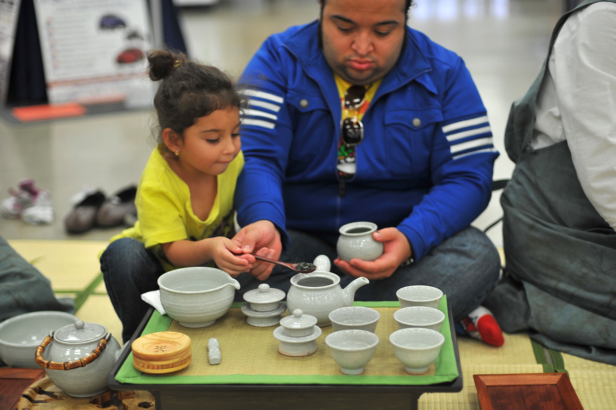 Luna Domenech assists her father, Lauro Domenech, 501st Military Intelligence Brigade intelligence analyst, put dried green tea leaves in a pot during the Korean tea culture and customs lecture at Osan Air Base, Republic of Korea, Oct. 23, 2013. There was an open invitation to anyone walking by the BX food court to have an opportunity to sit down, learn something new and enjoy a hot cup of green tea. (U.S. Air Force photo/Staff Sgt. Emerson Nuñez)