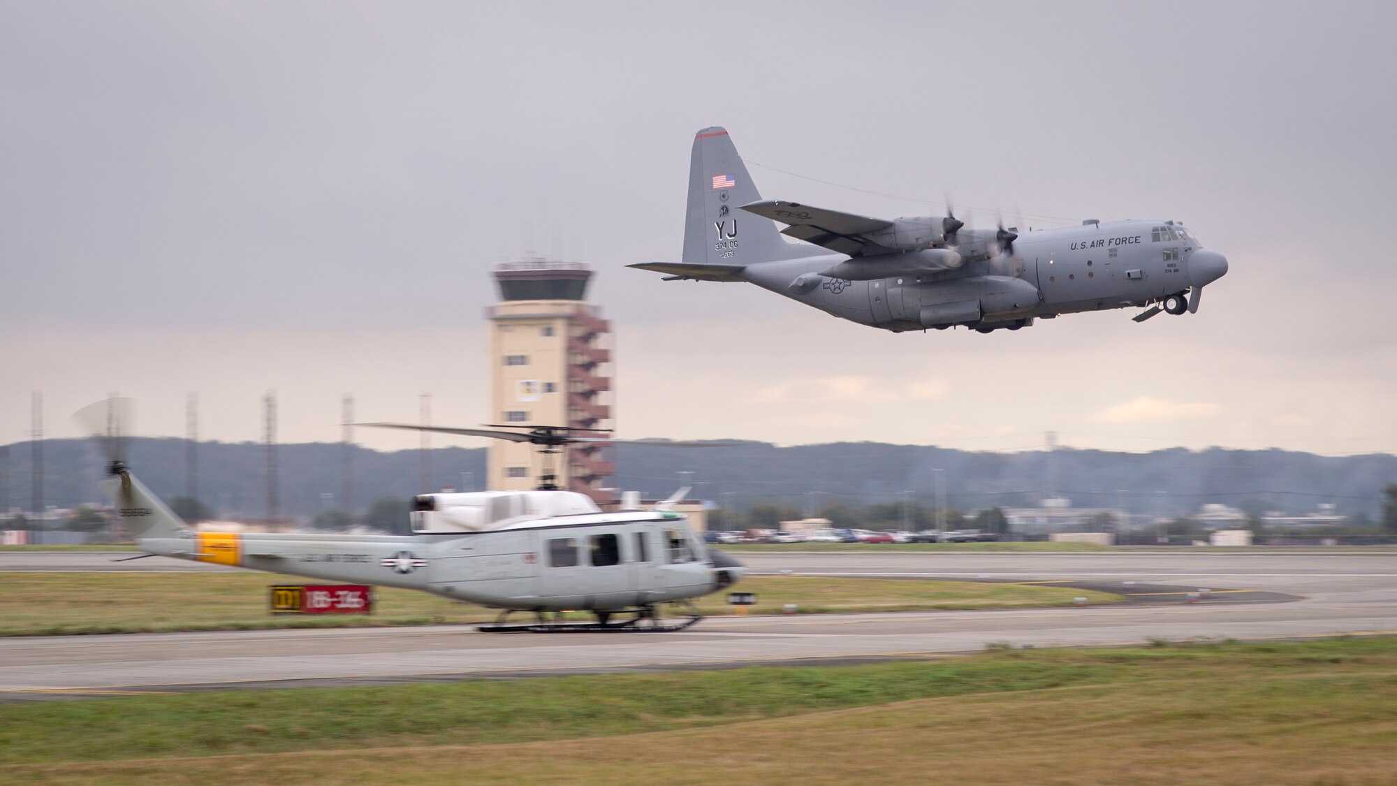 A C-130 Hercules takes off past a UH-1 Huey during a large-formation mission at Yokota Air Base, Japan, Oct. 22, 2013. During this mission, Team Yokota launched every aircraft currently stationed at Yokota. (U.S. Air Force photo by Captain Raymond Geoffroy/Released)