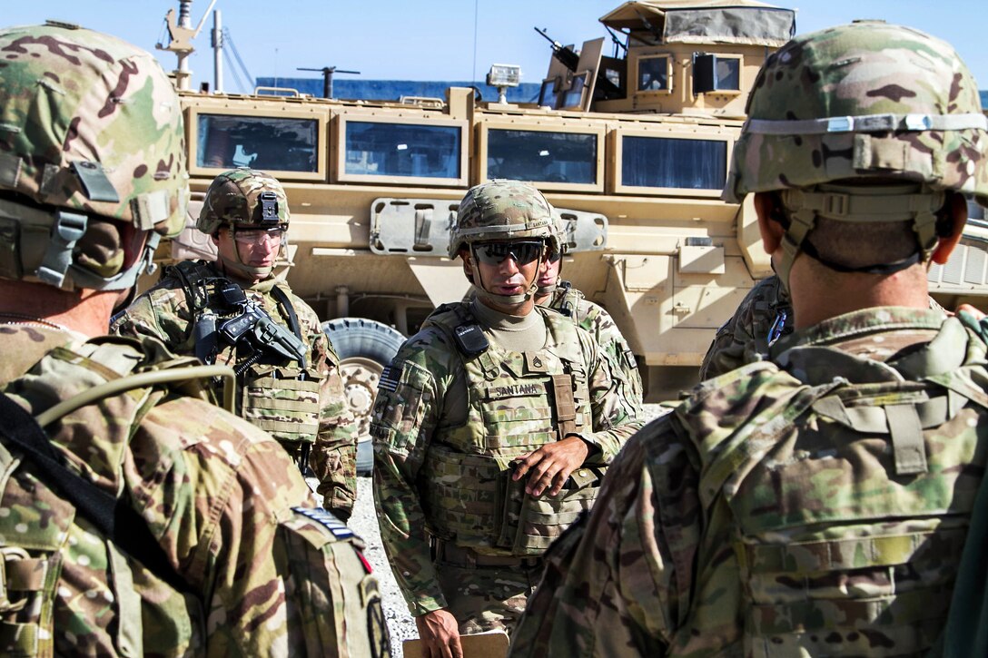U.S. Army Staff Sgt. Rafael Santana, center, conducts a safety brief with passengers before a mission on Kandahar Airfield, Afghanistan, Oct. 21, 2013. Santana, a convoy commander, is assigned to the 4th Infantry Division's Company C, Headquarters Battalion. 
