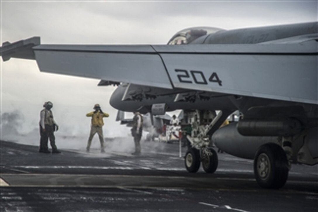 U.S. Navy Chief Petty Officer Osvaldo Delacruz, center, directs the pilot of an F/A-18E Super Hornet toward a catapult on the flight deck of the aircraft carrier USS George Washington (CVN 73) as the ship conducts flight operations in the South China Sea on Oct. 22, 2013.  The Super Hornet is attached to Strike Fighter Squadron 27 as part of the embarked Carrier Air Wing 5.  