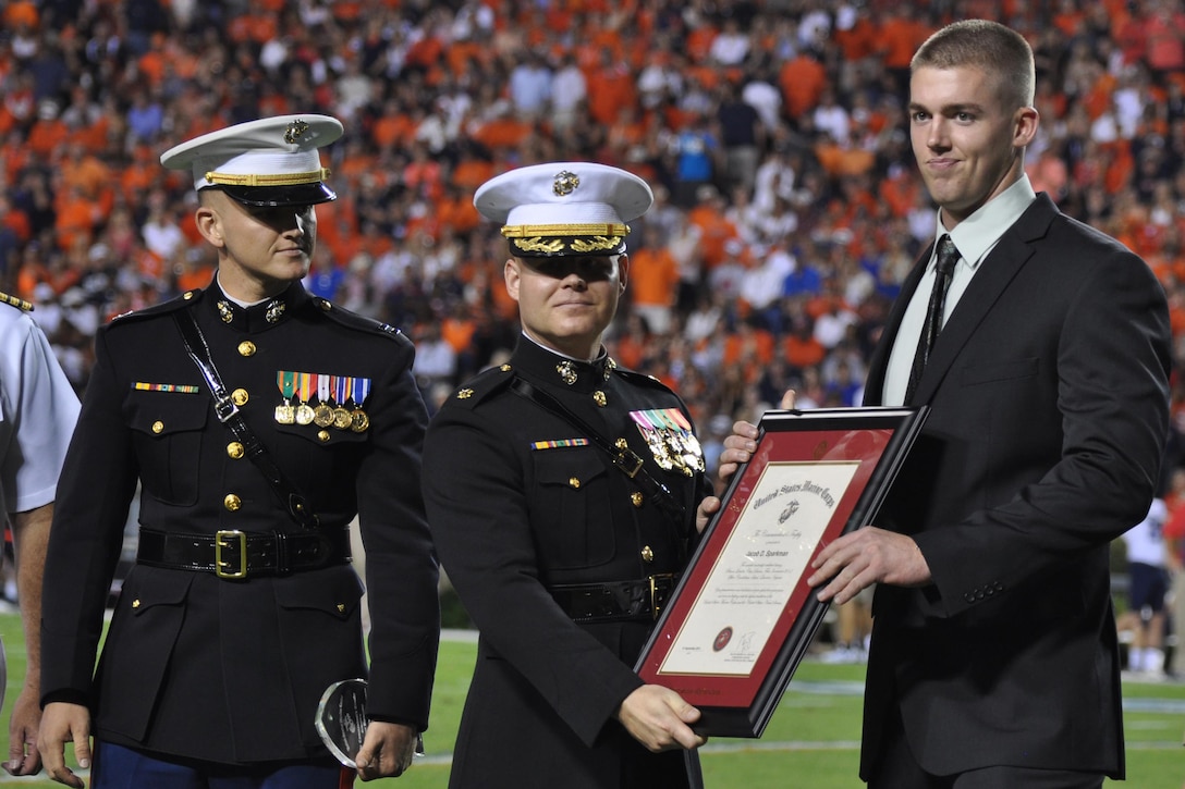 From Left, Capt. Joseph Goll, officer selection officer for Recruiting Station Montgomery, and Maj. Michael Hays, commanding officer, recruiting station Montgomery, present Jacob Sparkman with the CMC award for being the company honor grad for his OCS class during a game 