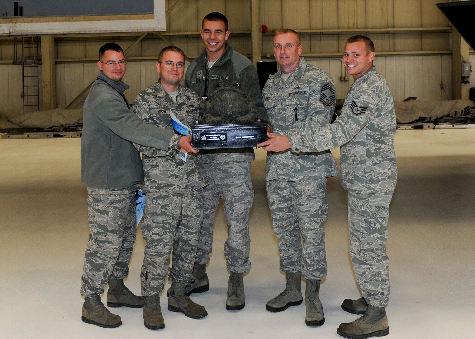 Chief Master Sgt. Jeffrey Burke, 28th Maintenance Group wing weapons manager (second from right), presents the Load Crew of the Quarter trophy to the 37th Aircraft Maintenance Unit weapons load crew team at Ellsworth Air Force Base, S.D., Oct. 18, 2013. Competition between units was intense, with the 37th AMU team finishing under a minute faster then all other teams and fewer points deductions – clenching the win for the quarter. (U.S. Air Force photo by Senior Airman Anania Tekurio/Released) 