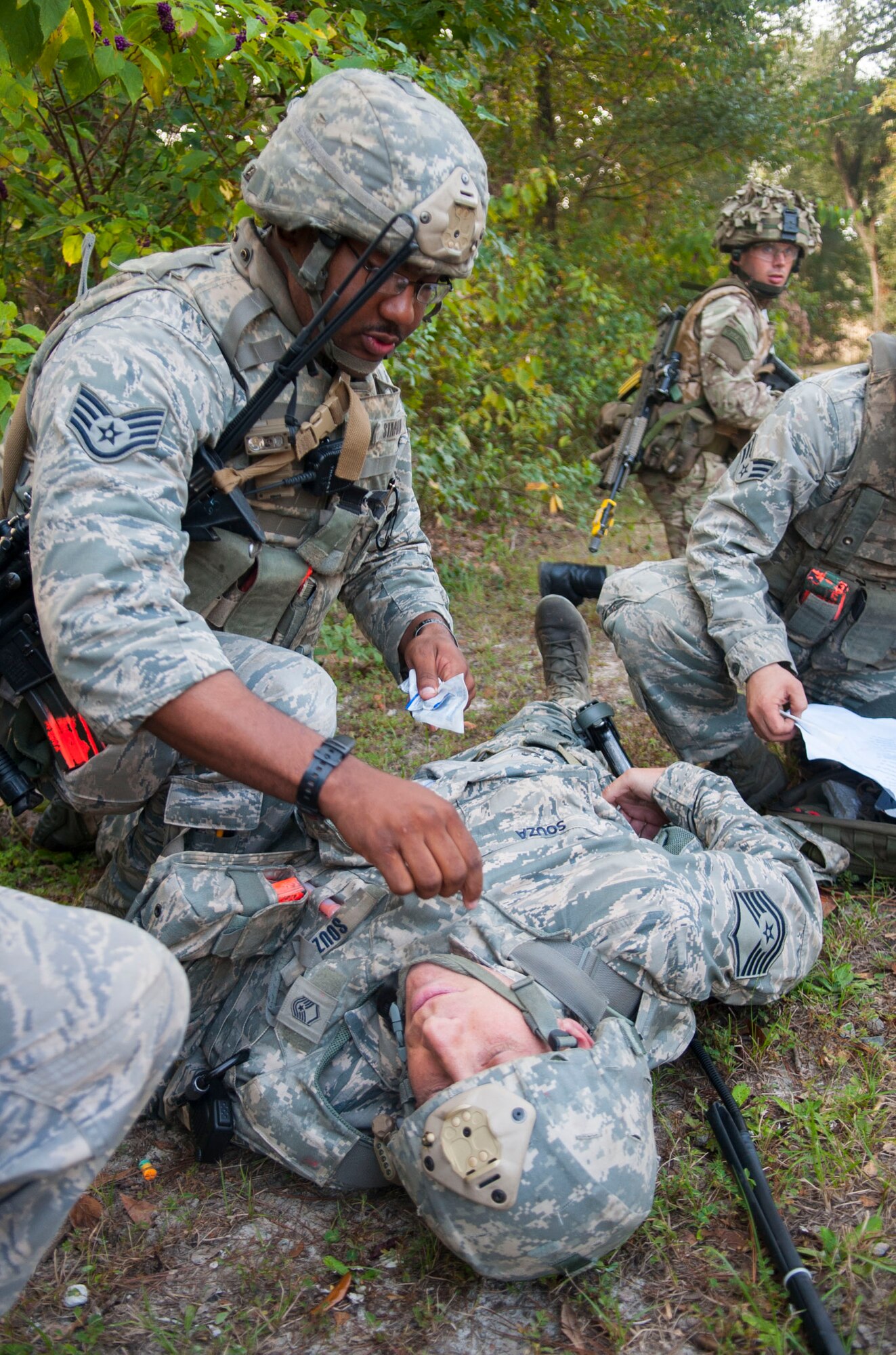 U.S. Air Force Staff Sgt. Felix Simon, 822d Base Defense Squadron, performs self-aid and buddy care on Master Sgt. Christopher Souza, during the GLOBAL EAGLE Exercise at Moody Air Force Base, Ga. Oct. 13, 2013. During the two-week exercise, members of the 820th Base Defense Group and the Royal Air Force Regiment conducted improvised explosive device procedures, tactical combat casualty care and combatives. (U.S. Air Force photo by Airman 1st Class Sandra Marrero/Released)

