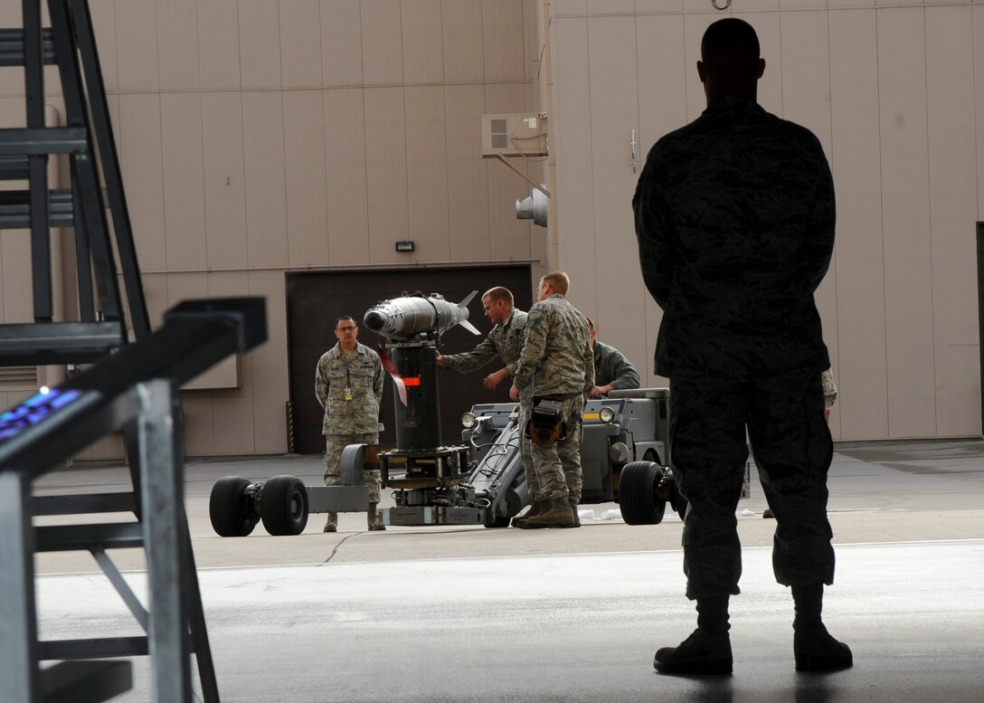 Airmen from the 37th Aircraft Maintenance Unit weapons load crew secure a mock guided bomb unit during the third quarter load crew competition at Ellsworth Air Force Base, S.D., Oct. 18, 2013. While the competition focused on rating each crew on efficiency, safety and the speed in loading munitions, it also served as a way of fostering camaraderie and friendly competition within the base’s weapons load crew units. (U.S. Air Force photo by Senior Airman Anania Tekurio/Released)