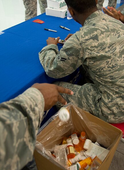 Staff Sgt. Stacy Welch, 2nd Security Forces Squadron, tosses an expired bottle of prescription medication into a box while Airman 1st Class Jordan McNair, 2nd SFS commander’s support staff, masks the personal identification on another bottle during Drug Take-Back Day on Barksdale Air Force Base, La., Oct. 23, 2013. More than 180 pounds of prescription medication was disposed of last year during the bi-annual event. The 2nd SFS and 2nd Medical Group work with the Drug Enforcement Agency to properly dispose of the medication collected. (U.S. Air Force photo/Staff Sgt. Amber Corcoran)