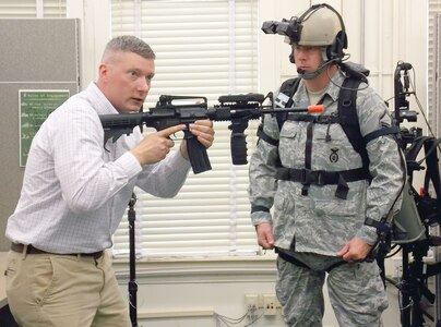 Dismounted Soldier Training System site lead Jacob Patrick demonstrates the proper method of holding the weapon in order to enact the virtual world sensor to Air Force Master Sgt. Jeremiah White. (Army Photo Courtesy of HHC, Southern Training Division 75th Training Command)