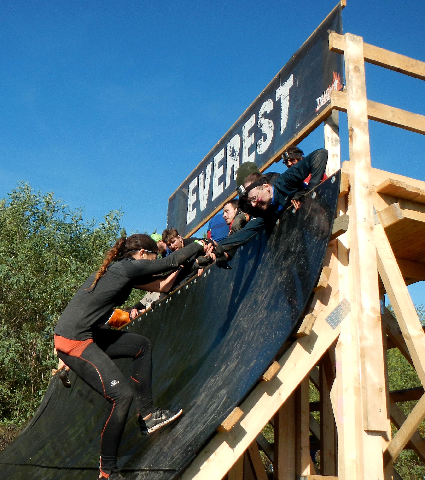 Fellow challengers help another team’s competitor over the Everest wall Oct. 19, 2013, during the Tough Mudder in Berlin, Germany. The challenge consisted of a 13-mile course filled with 30 obstacles designed by British Special Forces that test a participant’s strength, stamina, mental grit and camaraderie. (U.S. Air Force photo/Senior Airman Michael Battles)